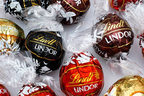 Primo piano di vari tartufi di cioccolato Lindt Lindor in involucri di alluminio di diversi colori.