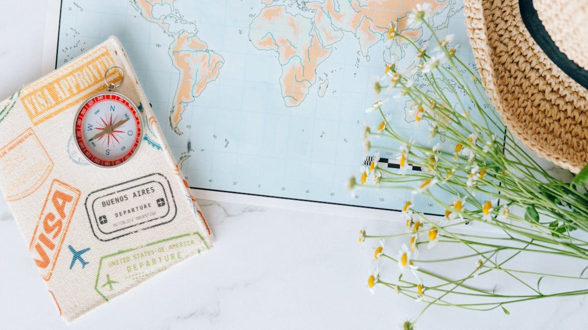 Pasaporte con brújula, mapa, sombrero de paja y flores silvestres, con temática de viajes.