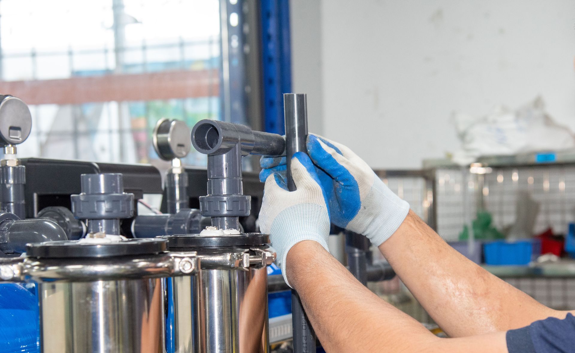 Person in blue gloves connecting a pipe to water filtration equipment. Person in blue gloves connecting a pipe to water filtration equipment.
