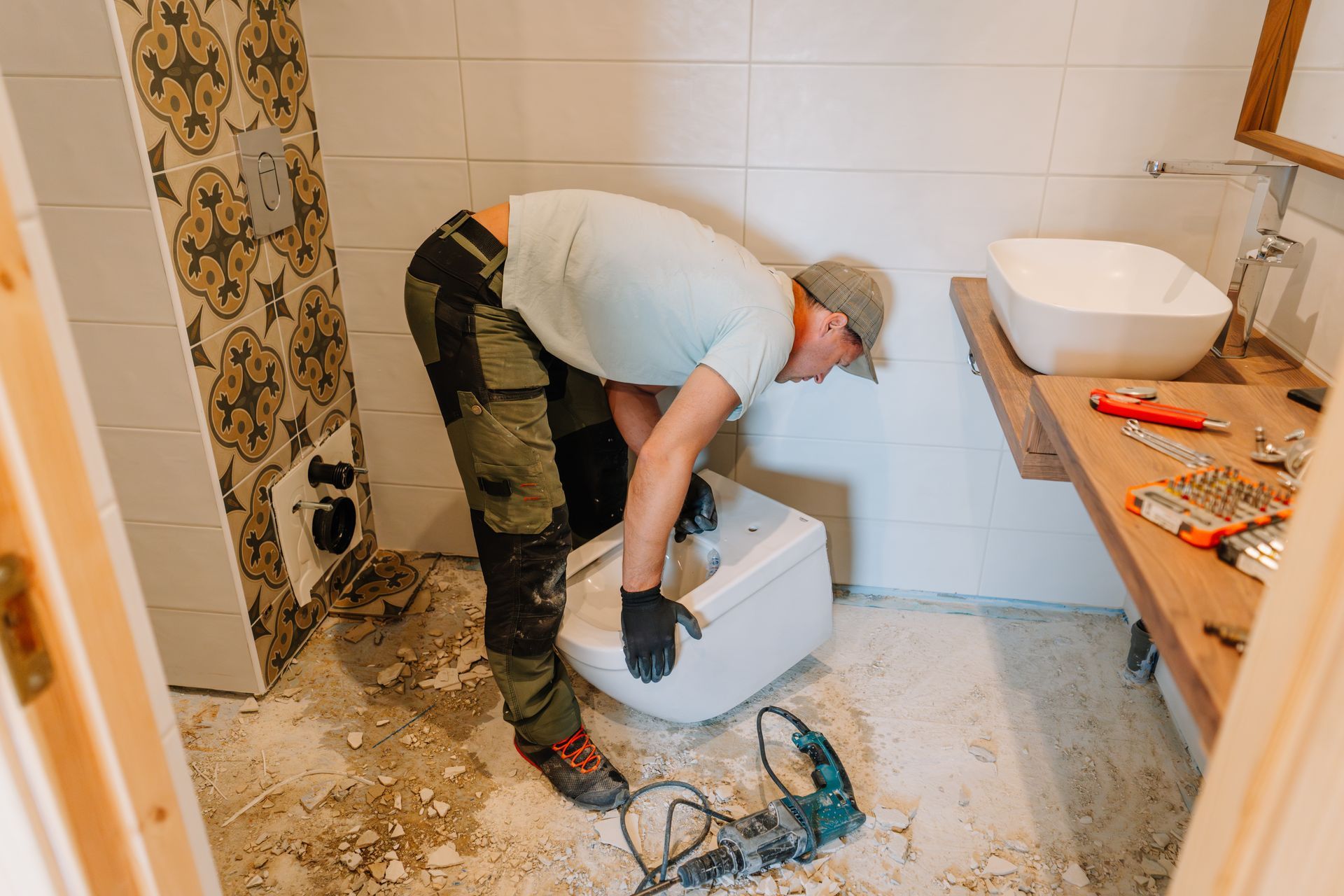 Person installing a toilet in a bathroom with exposed drywall and a sink. Person installing a toilet in a bathroom with exposed drywall and a sink.