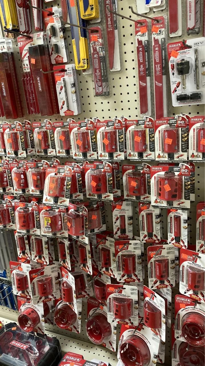 Rows of red hole saws displayed in a hardware store.