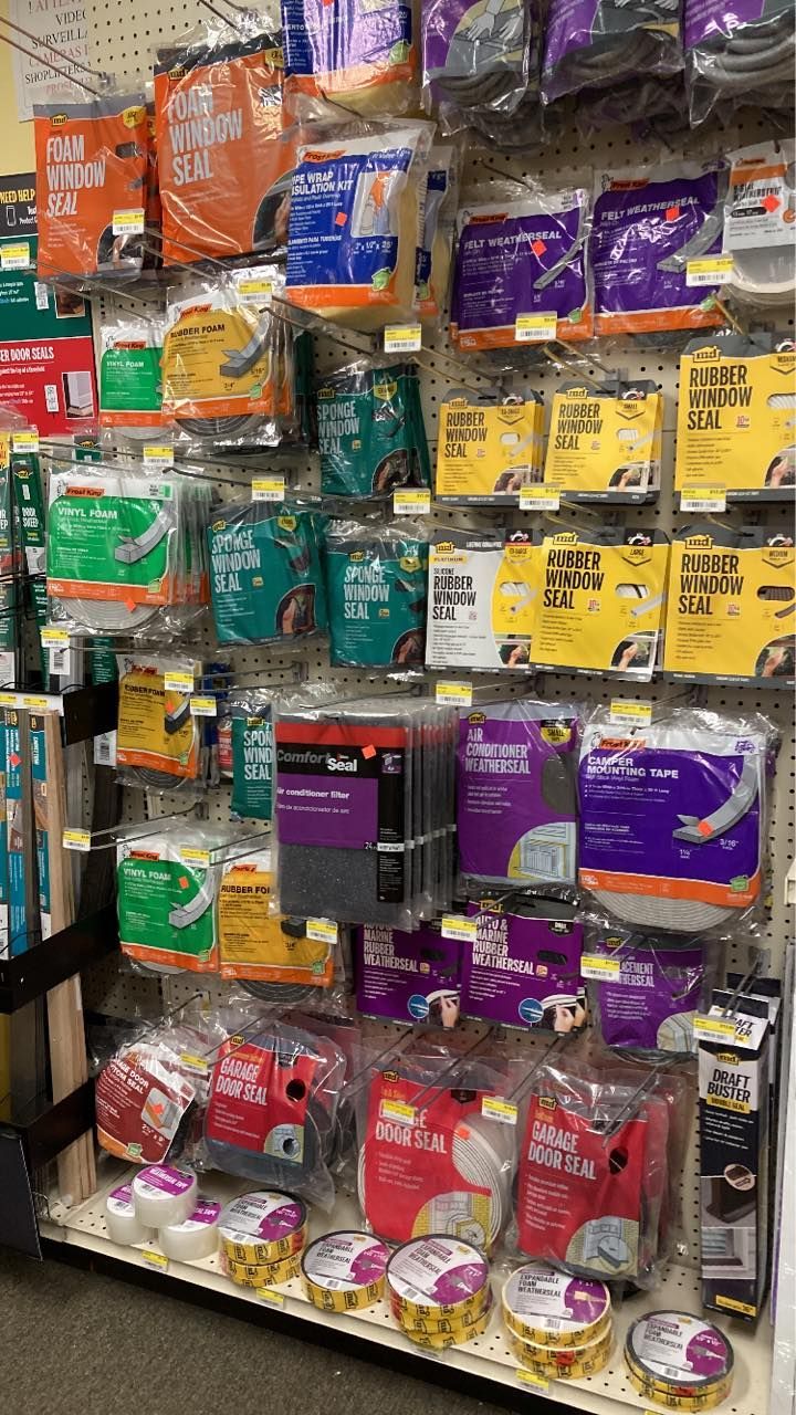 Shelves stocked with various paint supplies in a retail store, featuring different colors of paint buckets and accessories.
