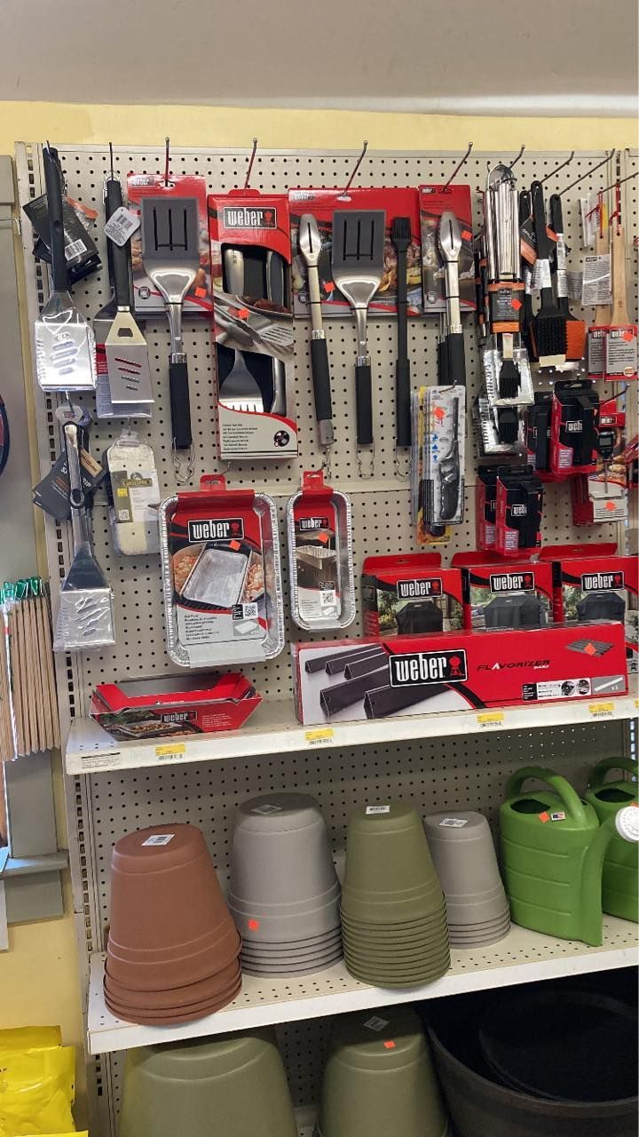 Grilling tools and gardening pots displayed on store shelves.