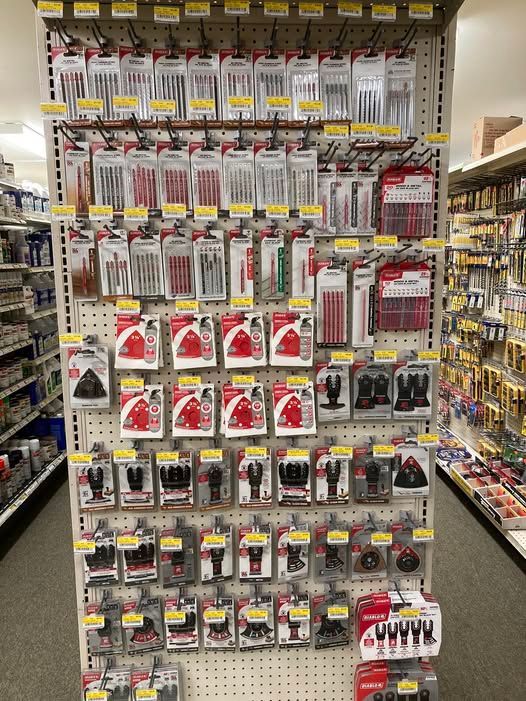 Shelves stocked with various hardware tools, mainly red and silver, in a store aisle.