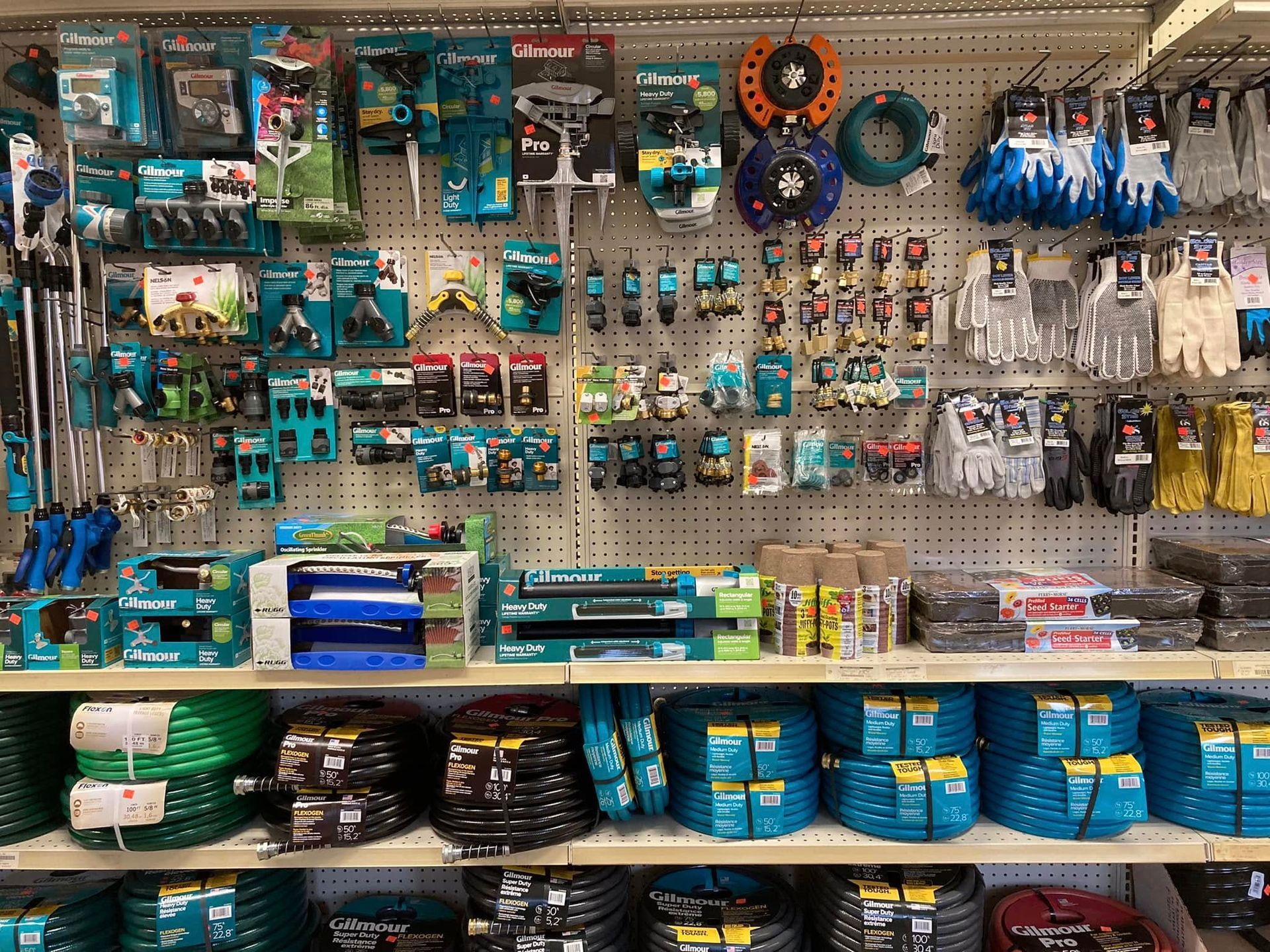 Shelves stocked with various gardening tools and supplies in a hardware store.