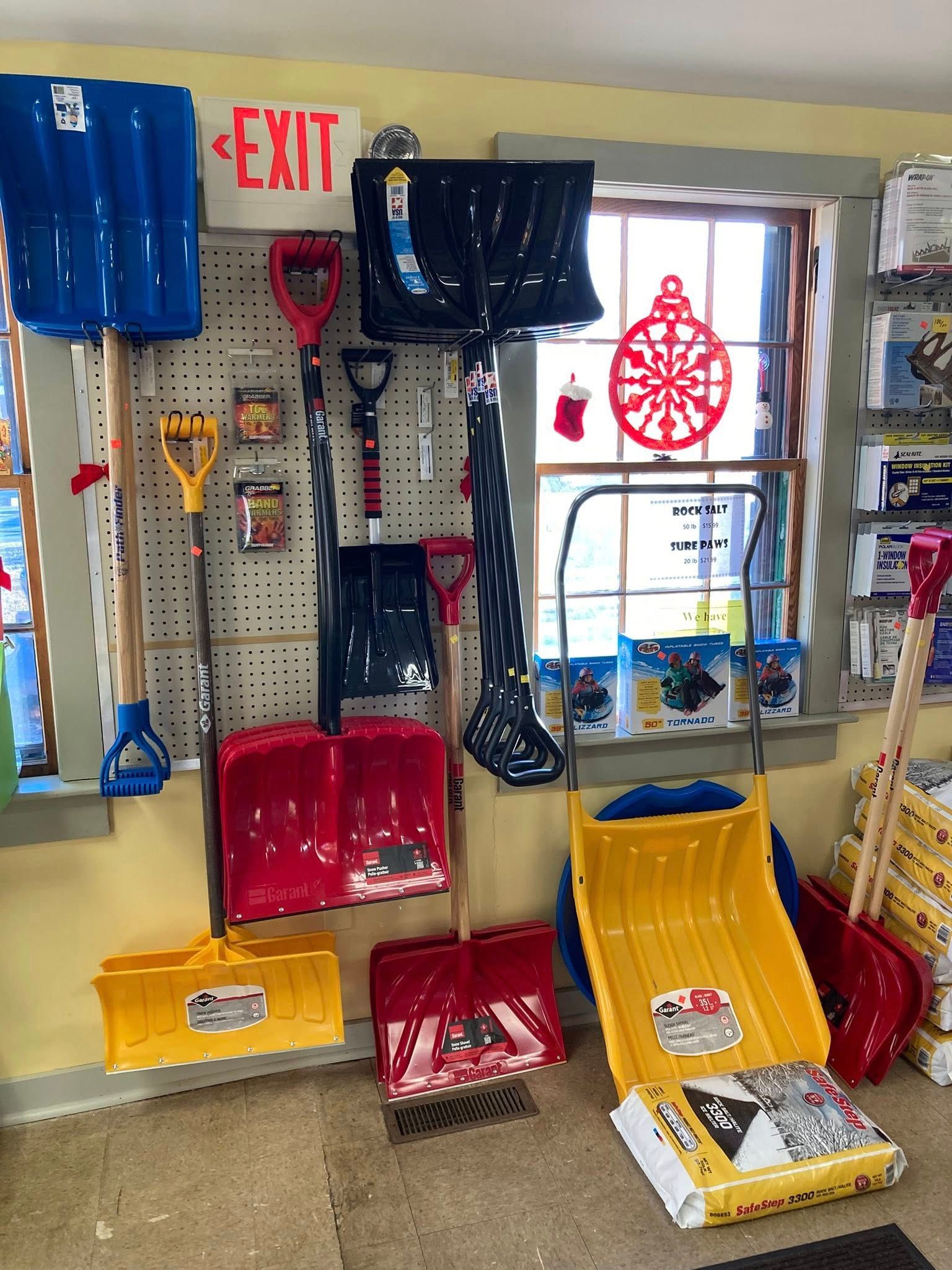 Snow shovels of various colors and sizes displayed in a store, including red, blue, and yellow.
