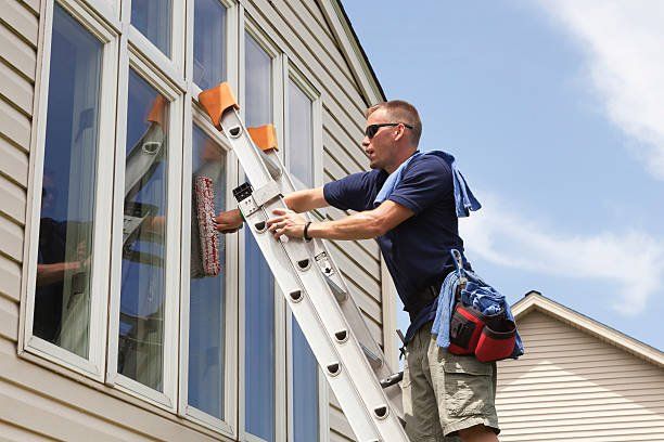 man on ladder performing window cleaning services