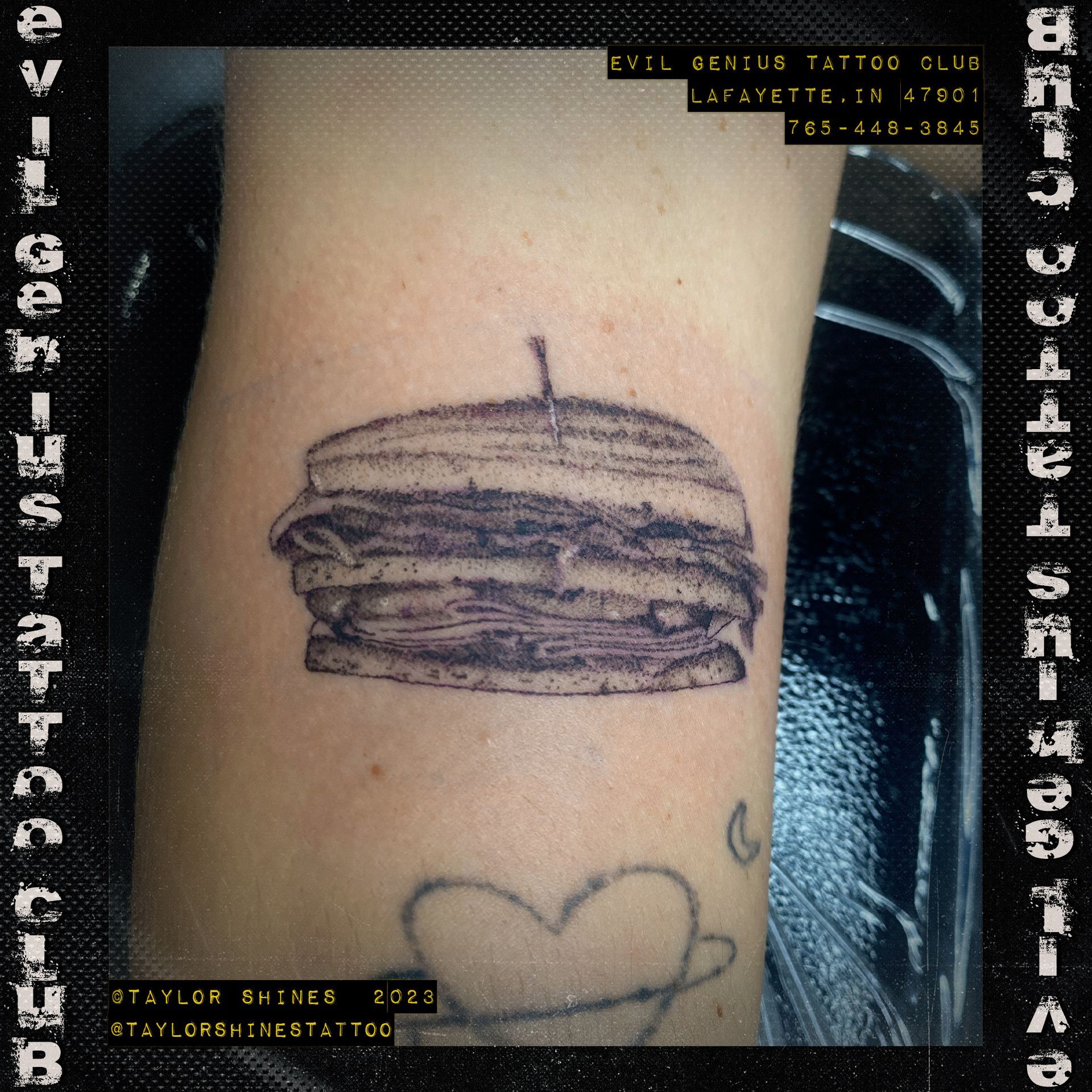 A person has a tattoo of a sandwich on their arm done by Taylor Shines.