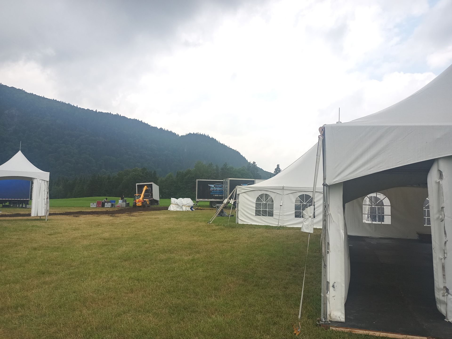 Un groupe de tentes dans un champ avec des montagnes en arrière-plan
