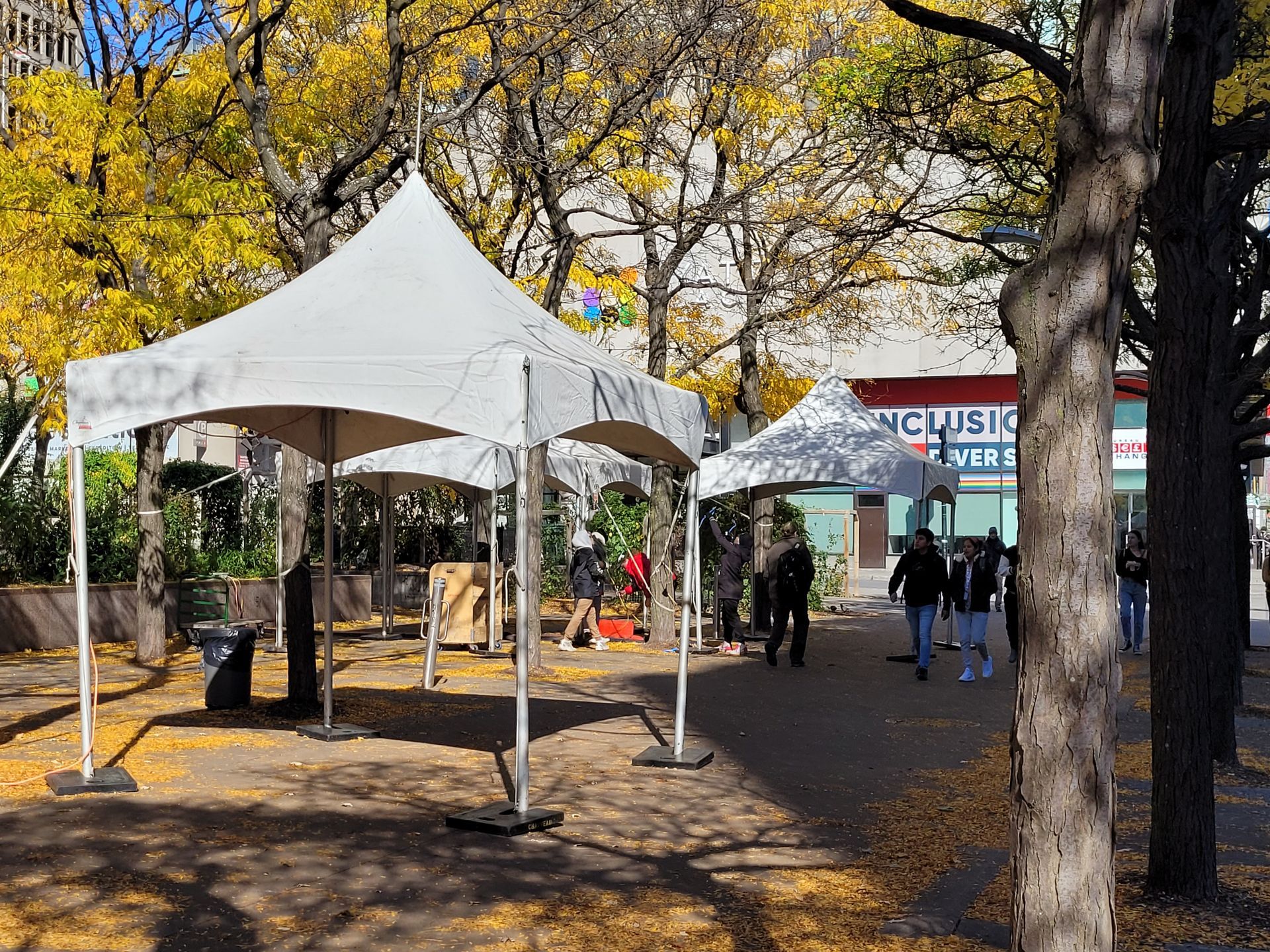 Un groupe de personnes marche sous des tentes dans un parc.