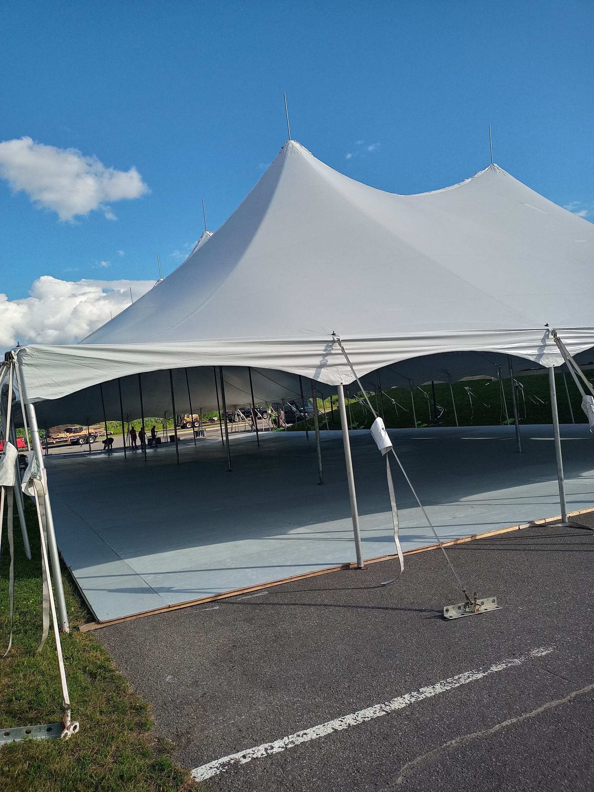Une grande tente blanche trône sur un parking.