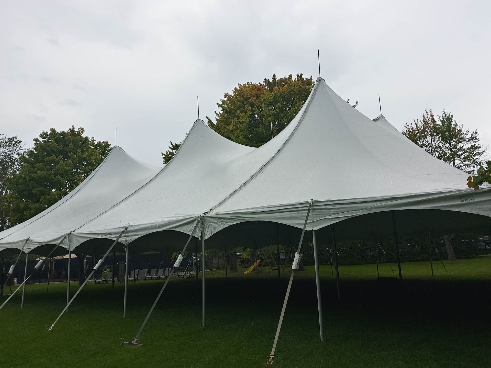 Une grande tente blanche est dressée au milieu d’un champ herbeux.