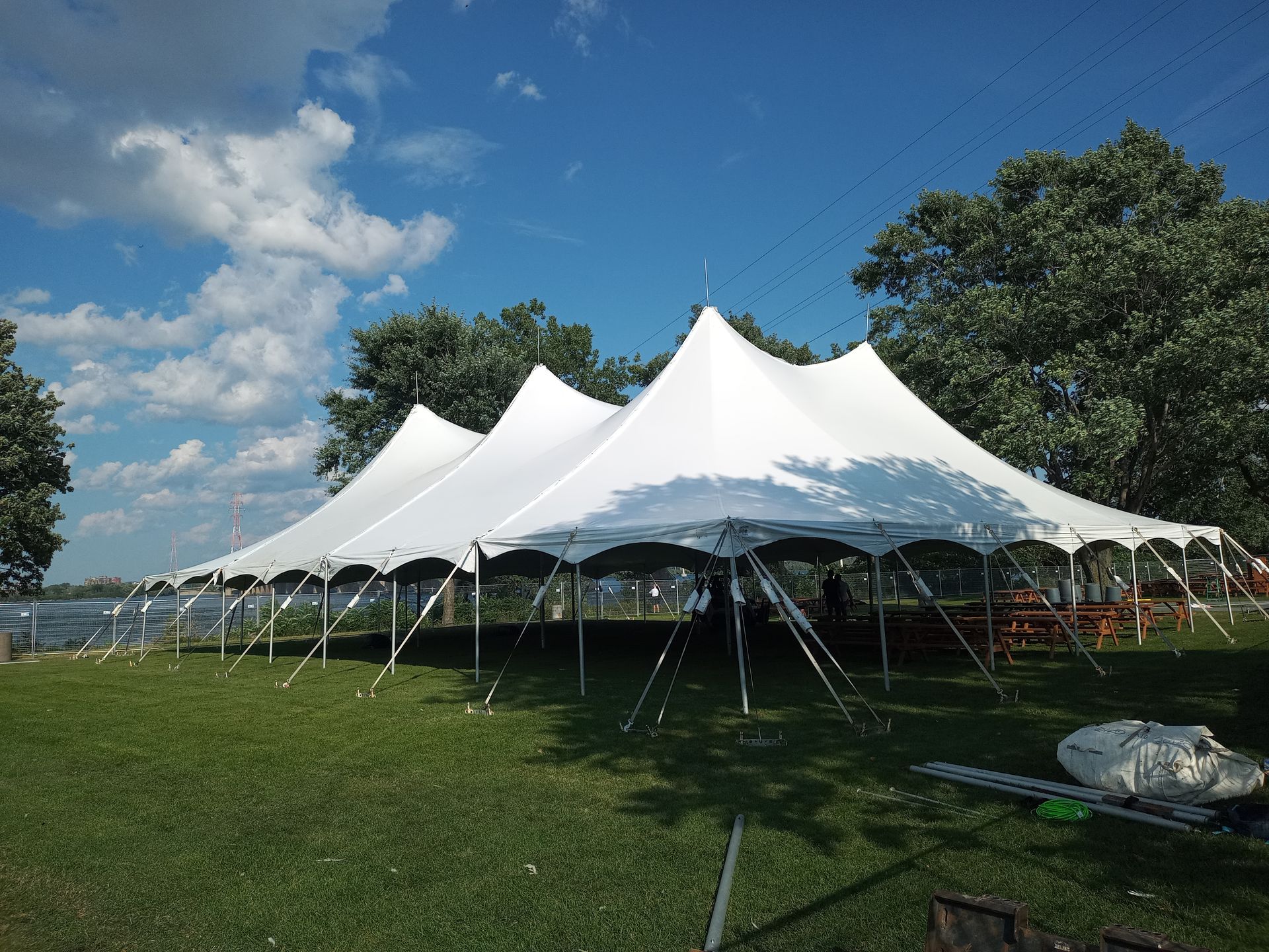 Une grande tente blanche est posée au sommet d’un champ verdoyant.