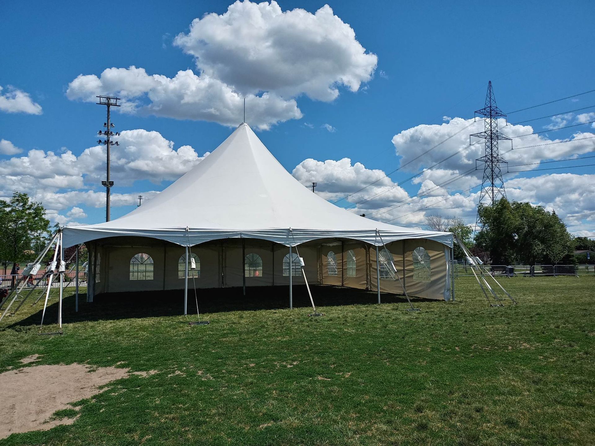 Une grande tente blanche est dressée au milieu d’un champ herbeux.