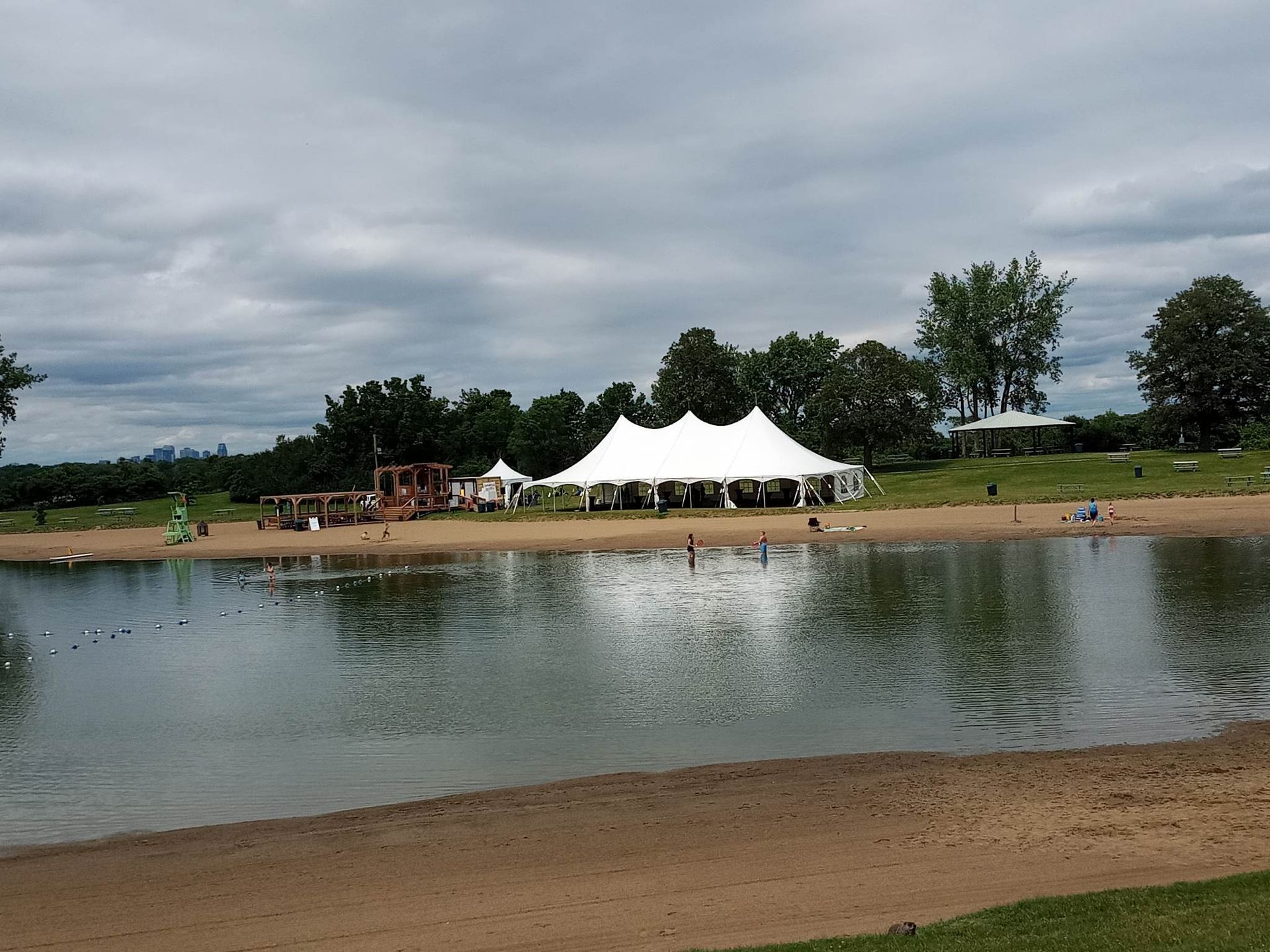 Une grande tente blanche se trouve au bord d’un lac