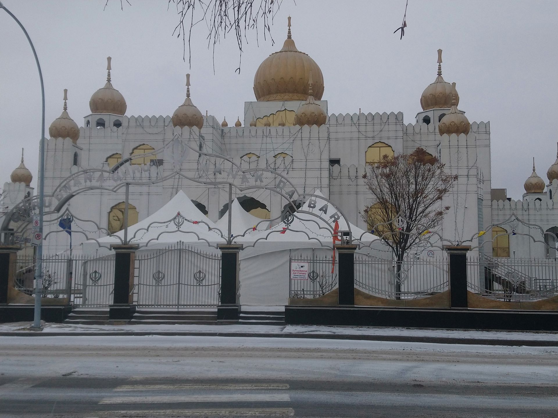 Un grand bâtiment blanc avec des dômes dorés et des tentes devant