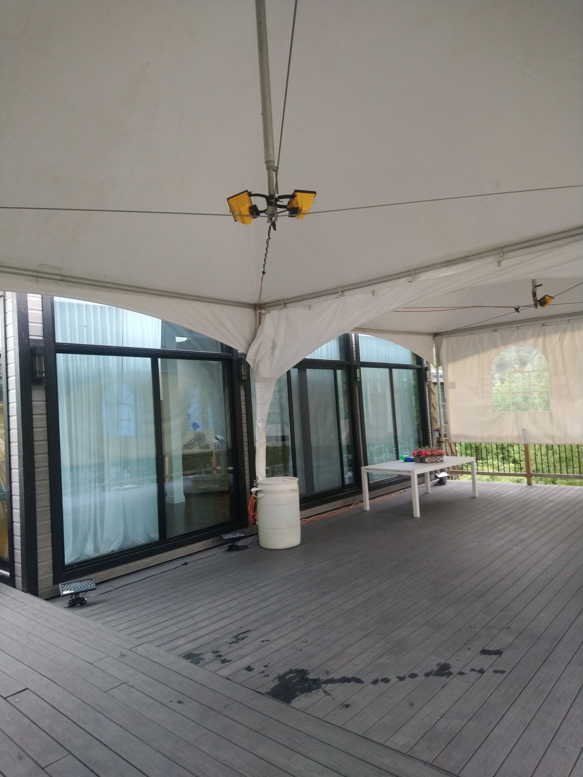 Une grande tente blanche est posée sur une terrasse en bois.