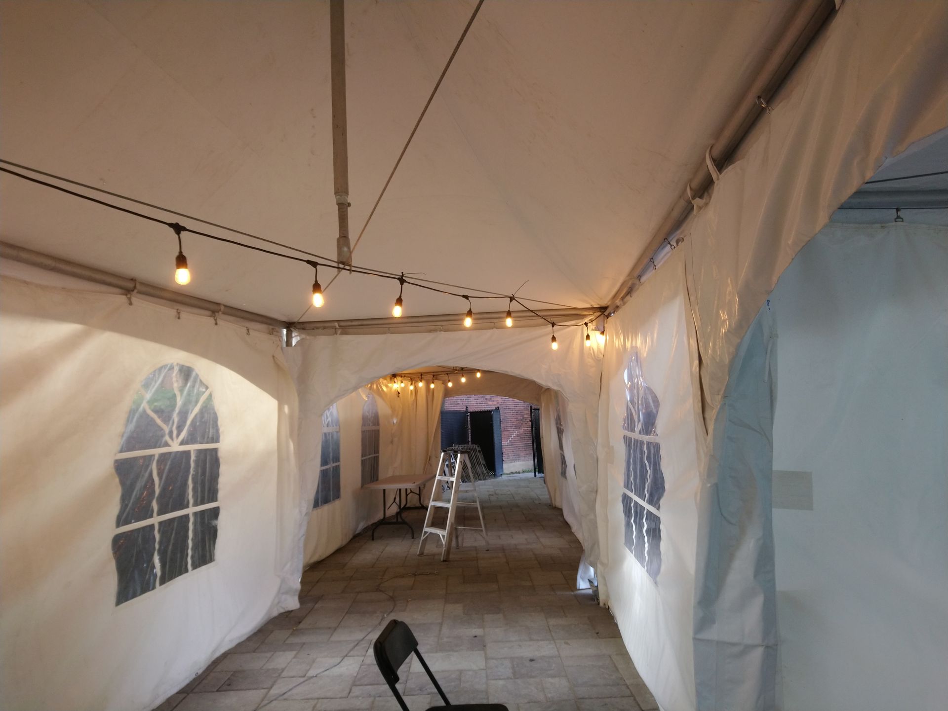 Un long couloir menant à une tente avec des lumières suspendues au plafond.