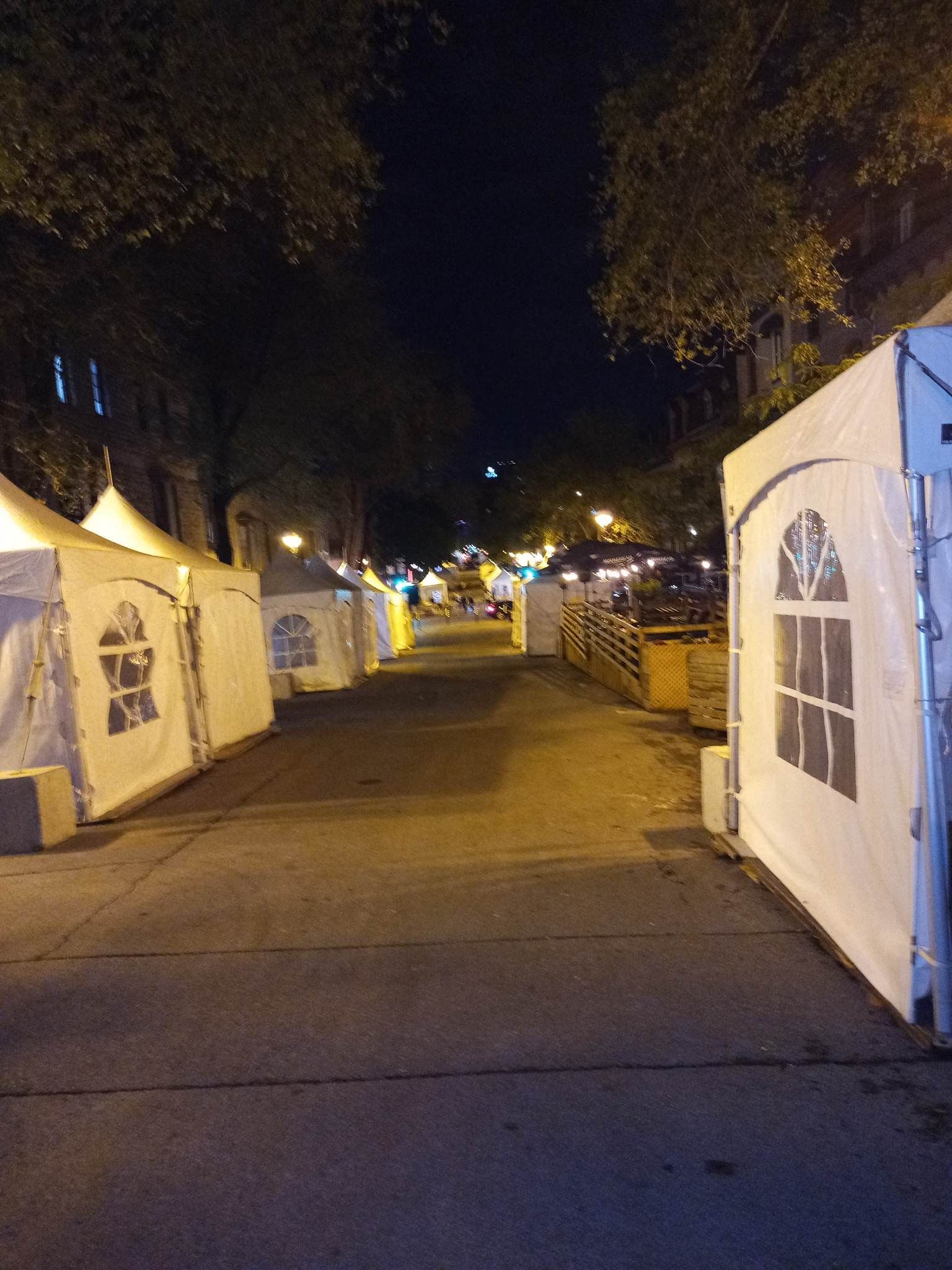 Une rangée de tentes sont alignées sur un trottoir la nuit
