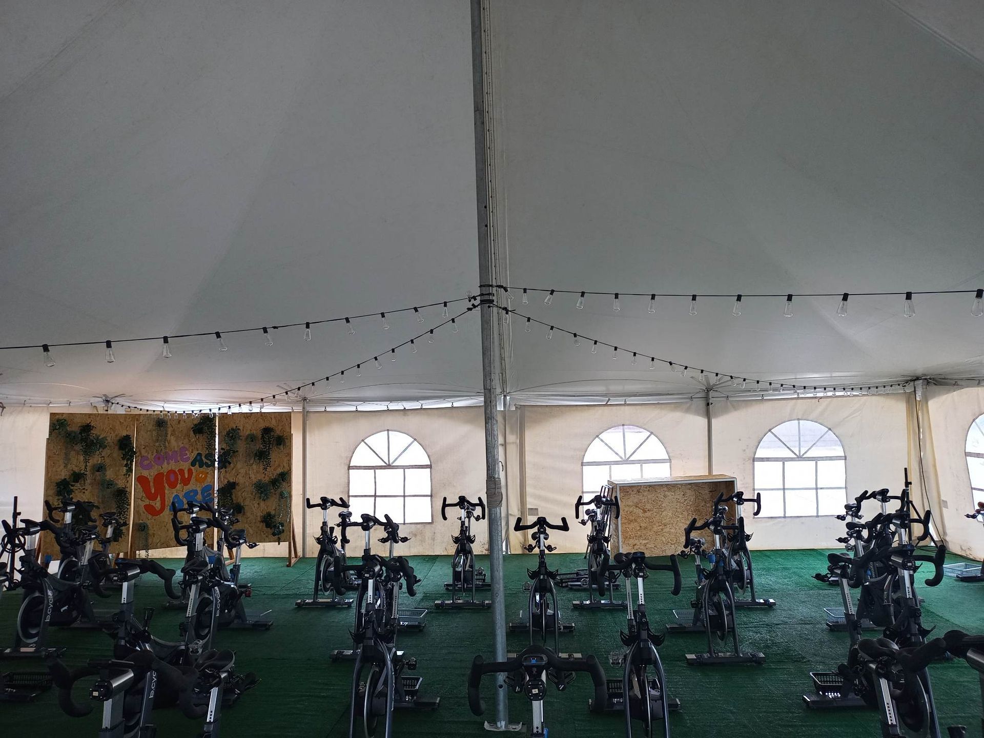 Une rangée de vélos d'exercice sous une tente dans une salle de sport