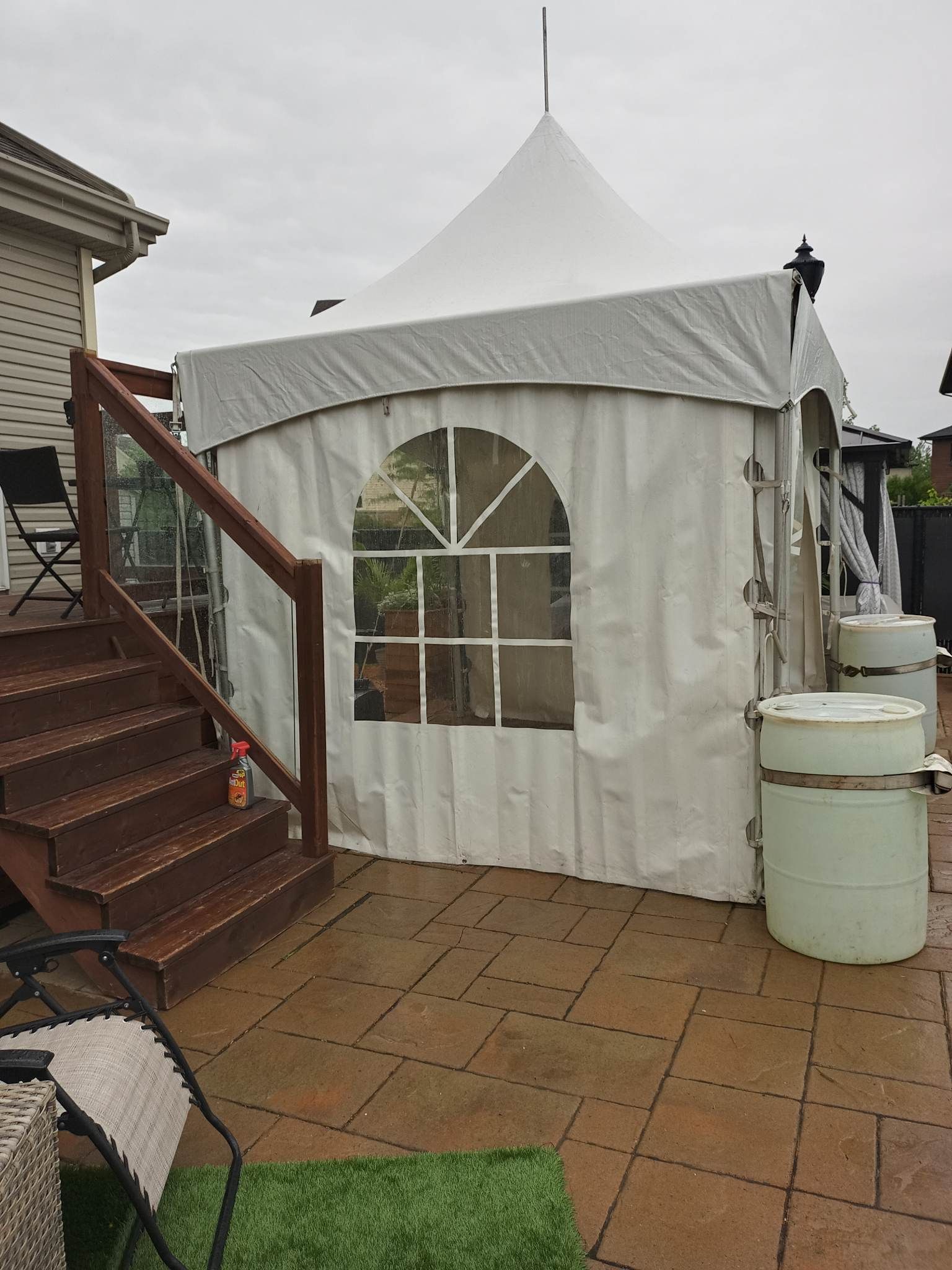Une tente blanche est installée sur une terrasse à côté des escaliers.