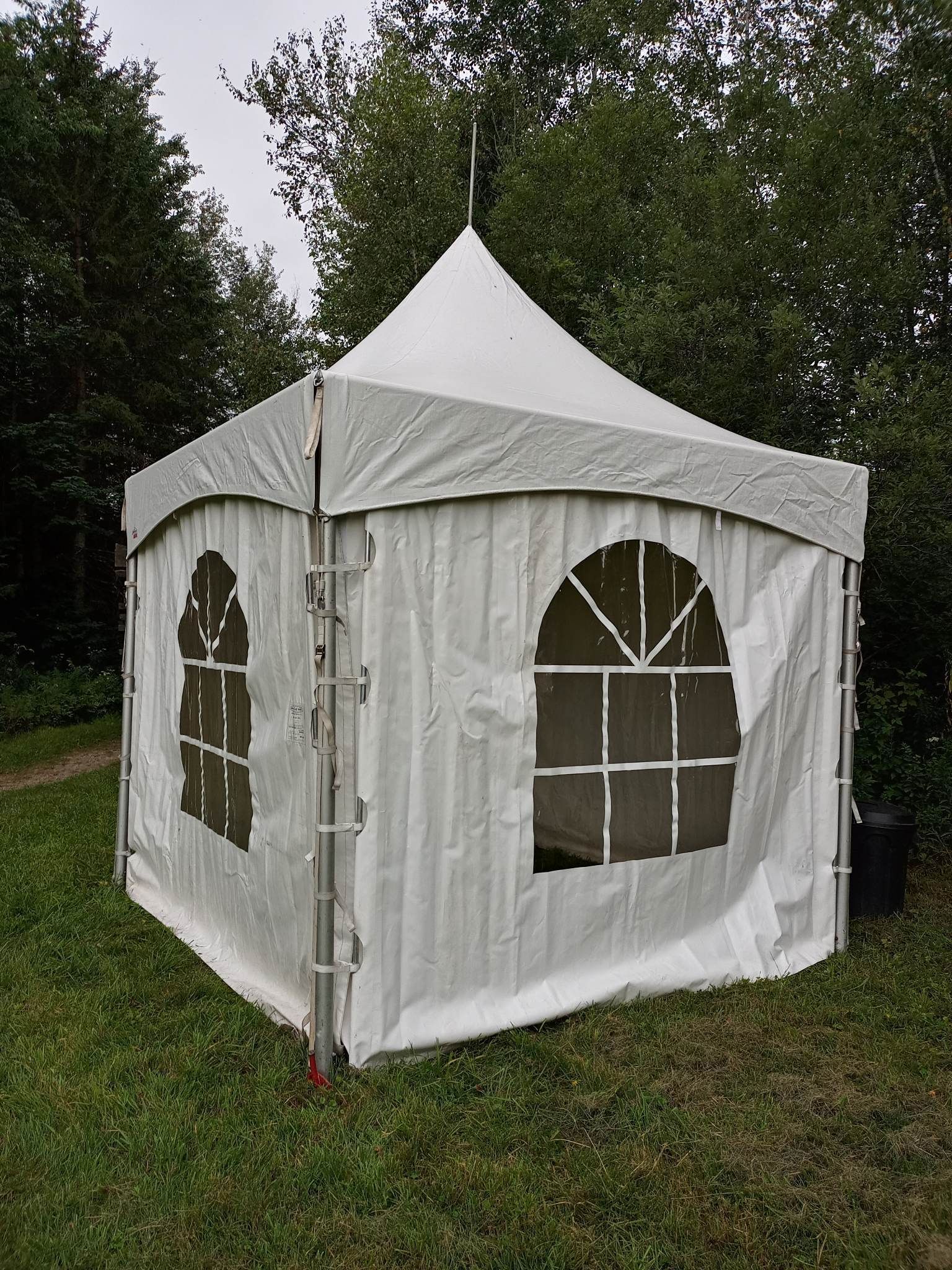 Une tente blanche est posée au sommet d’un champ verdoyant.