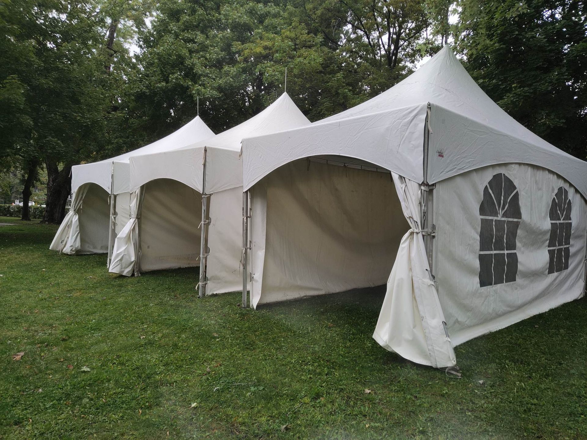 Une rangée de tentes blanches se dresse au sommet d’un champ verdoyant.