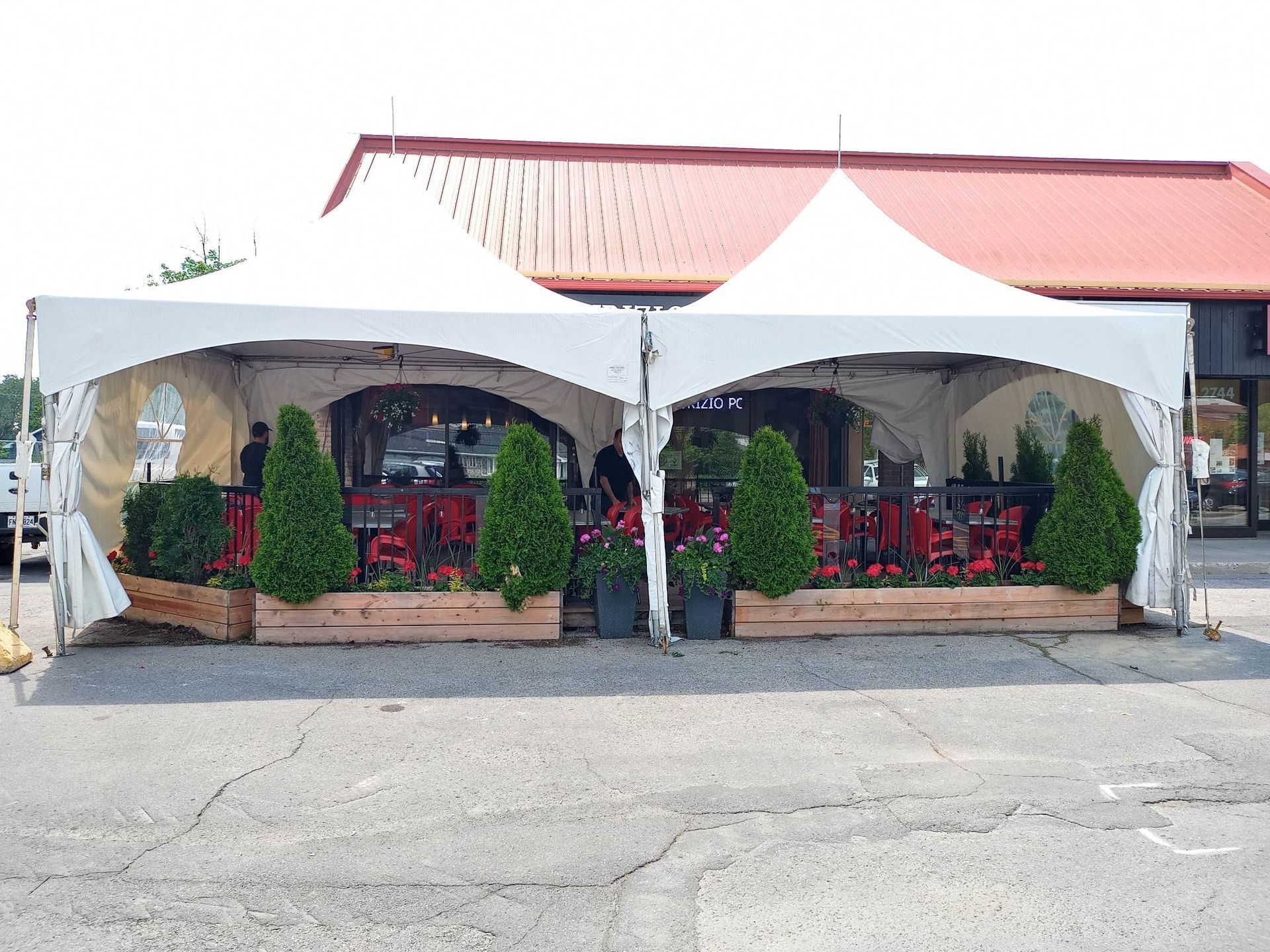 Deux tentes blanches sont installées sur un parking devant un immeuble.