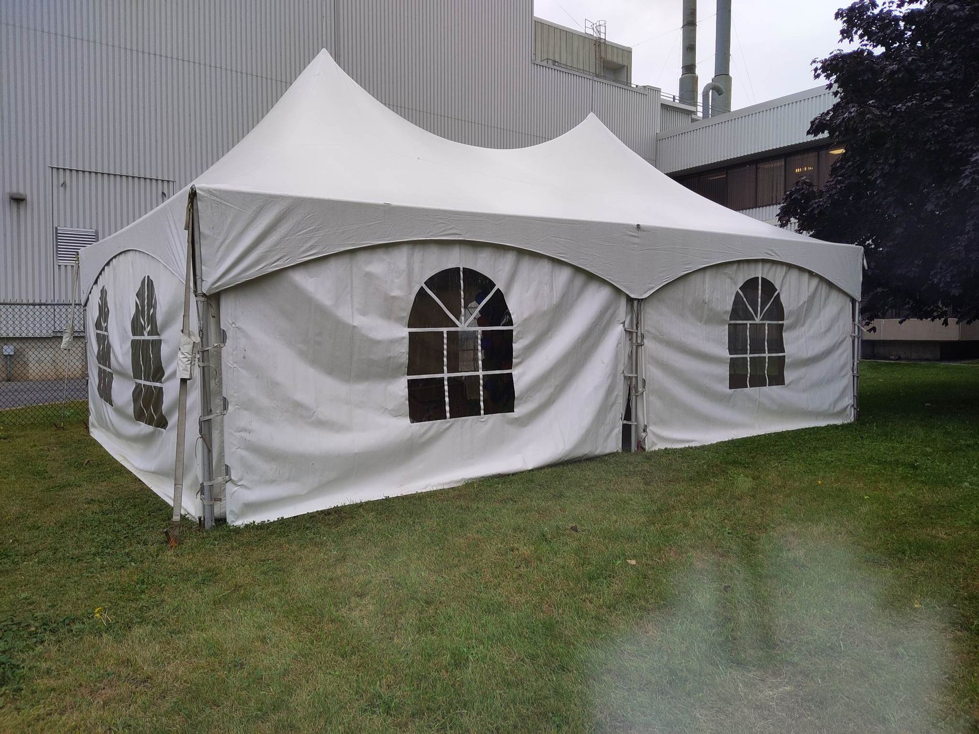 Une tente blanche est posée dans l’herbe devant un bâtiment