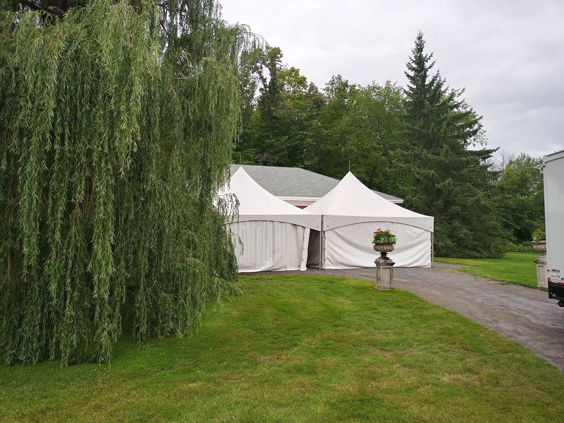 Une tente blanche est dressée au milieu d’un champ herbeux.