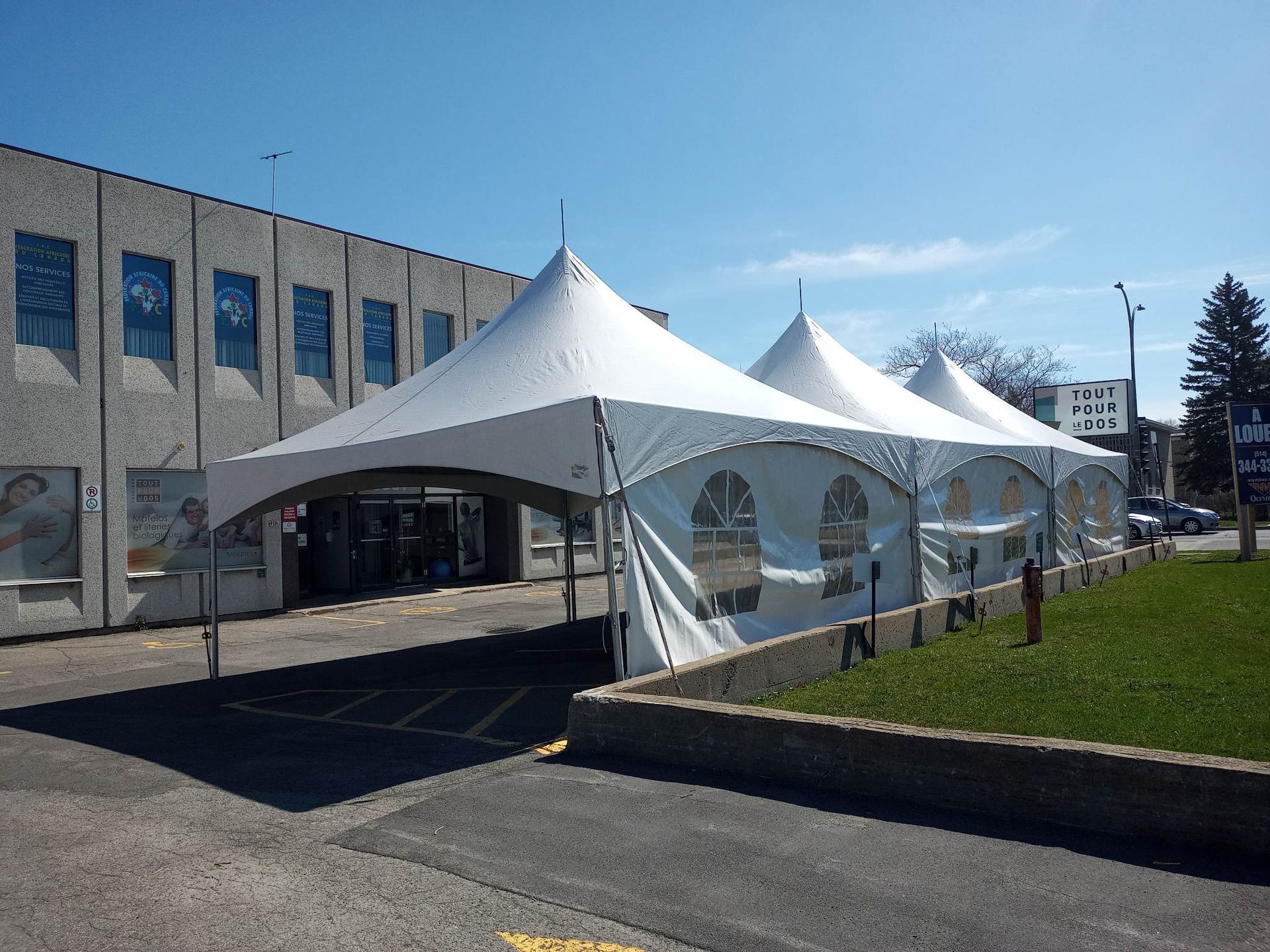 Une rangée de tentes blanches sont alignées devant un bâtiment