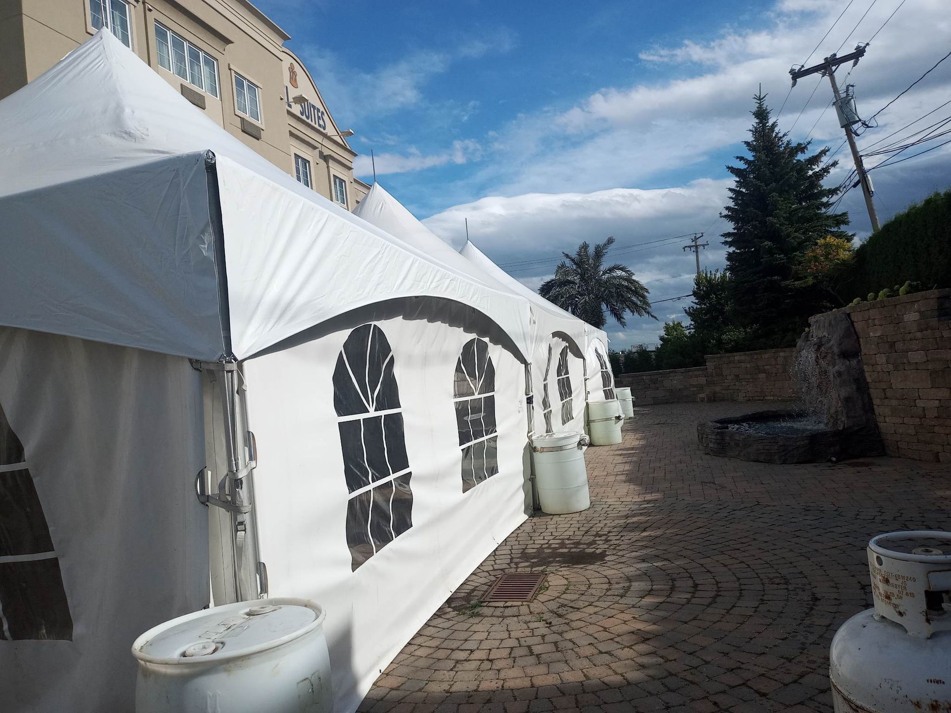 Une rangée de tentes blanches sont alignées sur un trottoir en brique