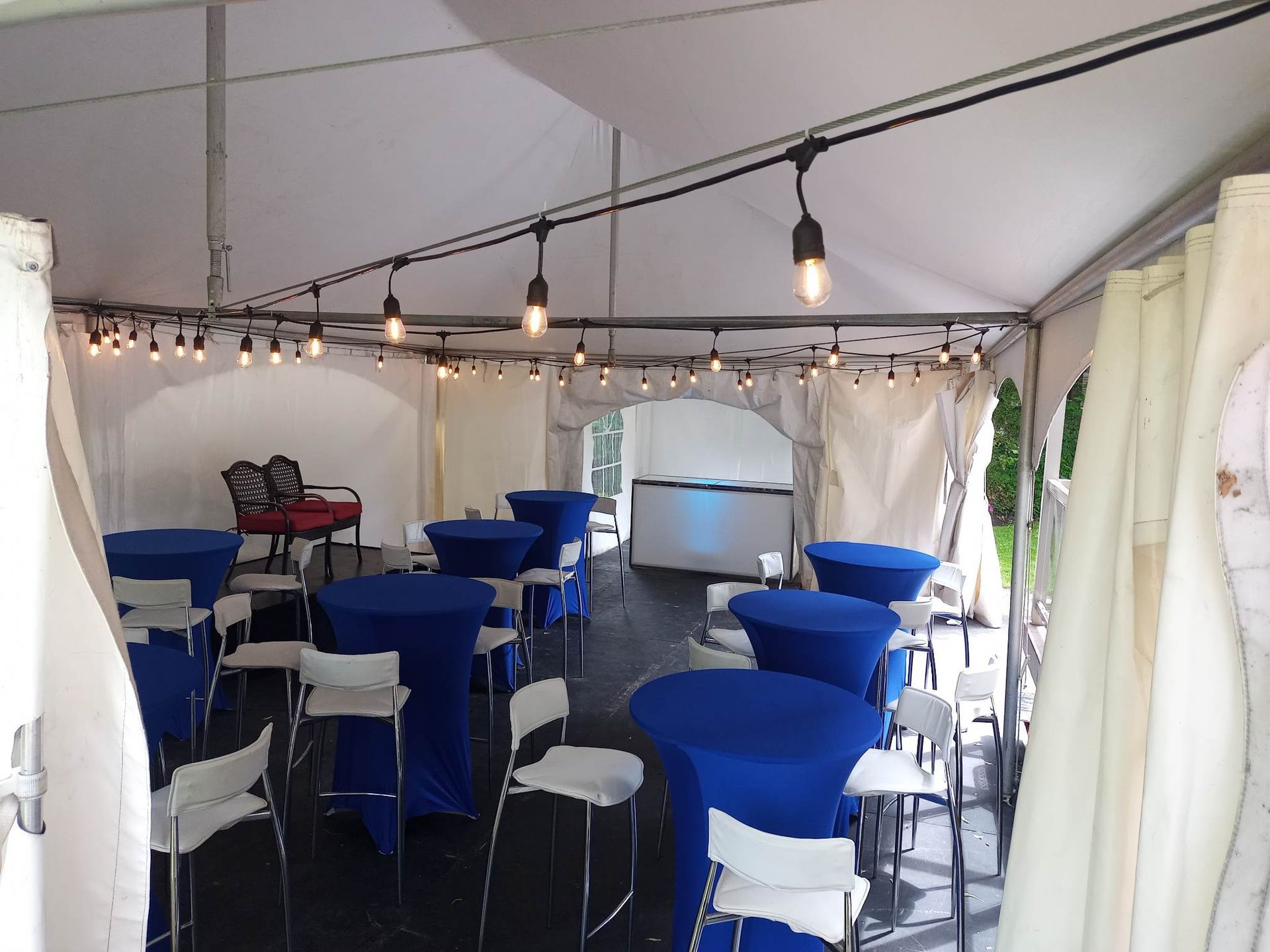 Une tente remplie de tables bleues et de chaises blanches