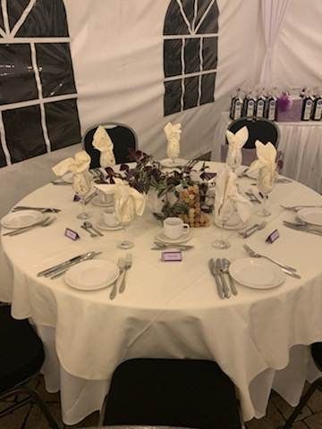 Une table dressée pour une réception de mariage sous une tente.
