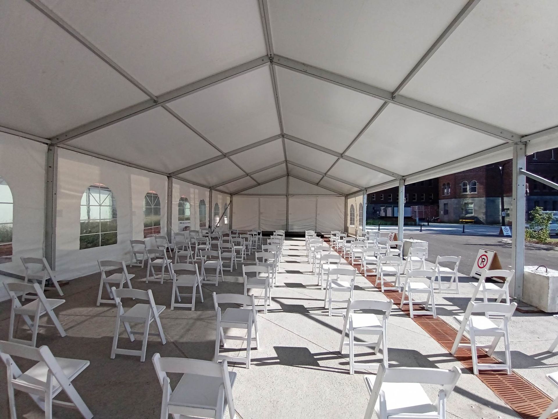 Rangées de chaises pliantes blanches sous une tente blanche