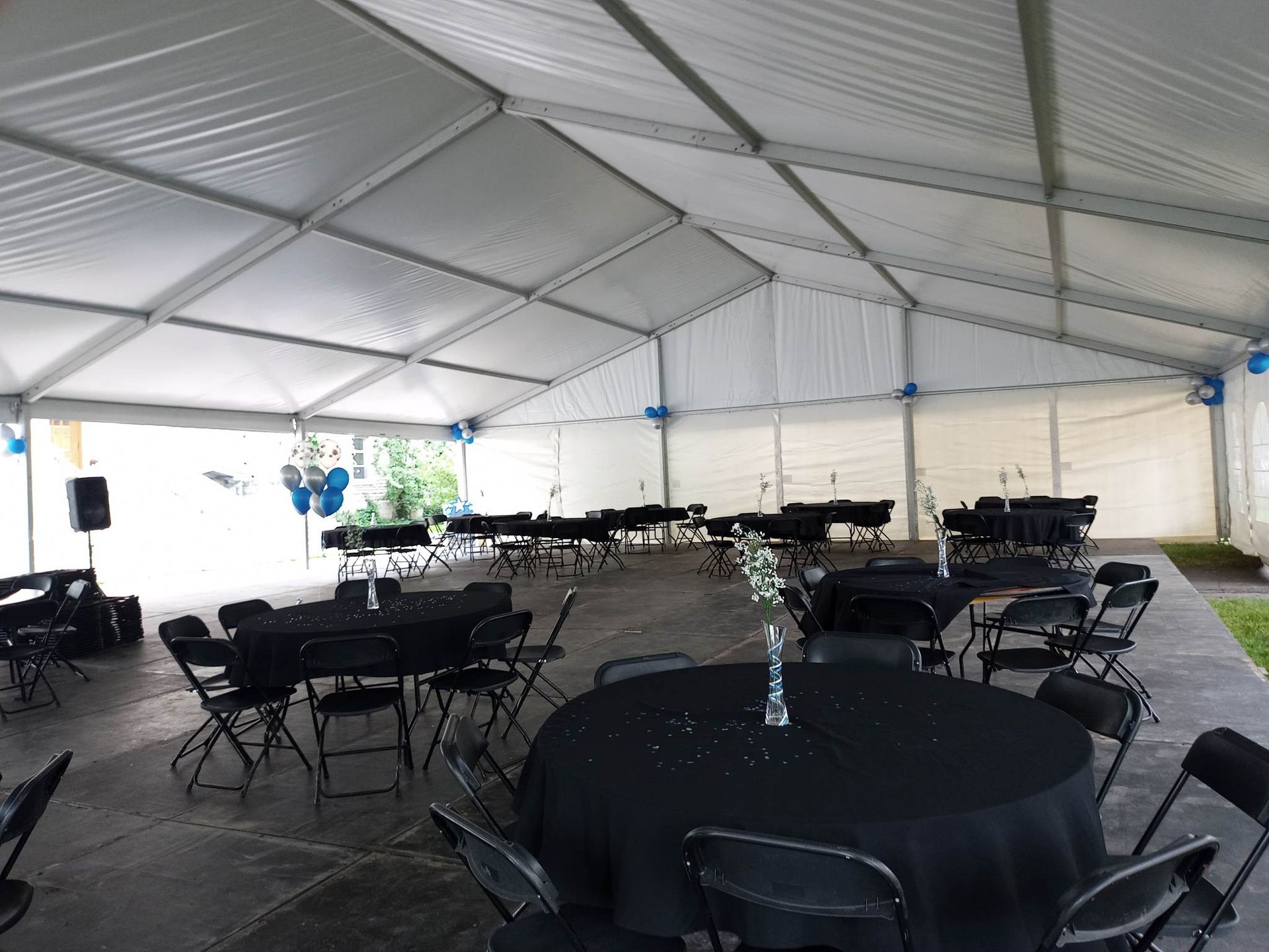 Une grande tente blanche avec des tables et des chaises noires