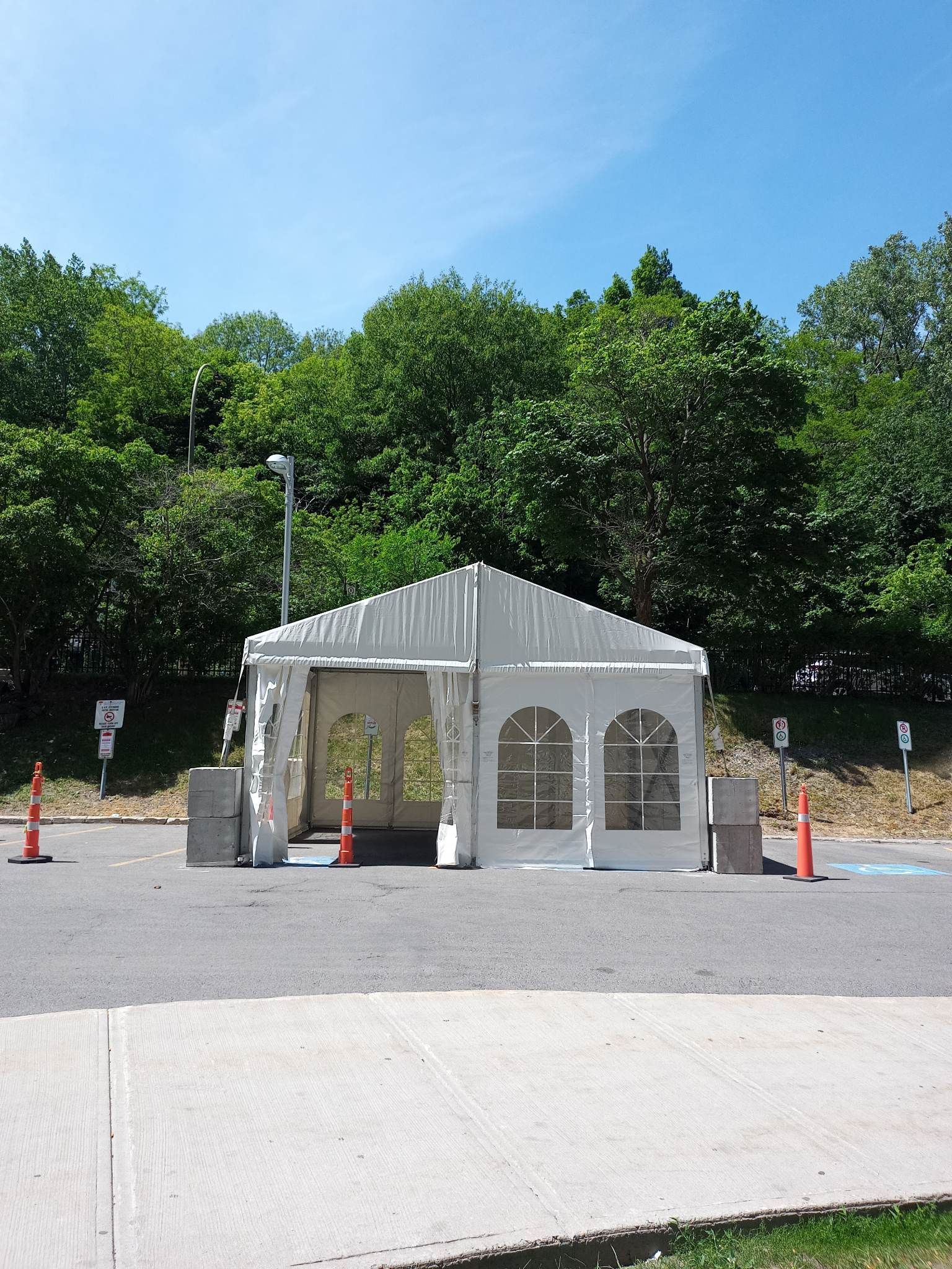Une tente blanche dans un parking avec des arbres en arrière-plan
