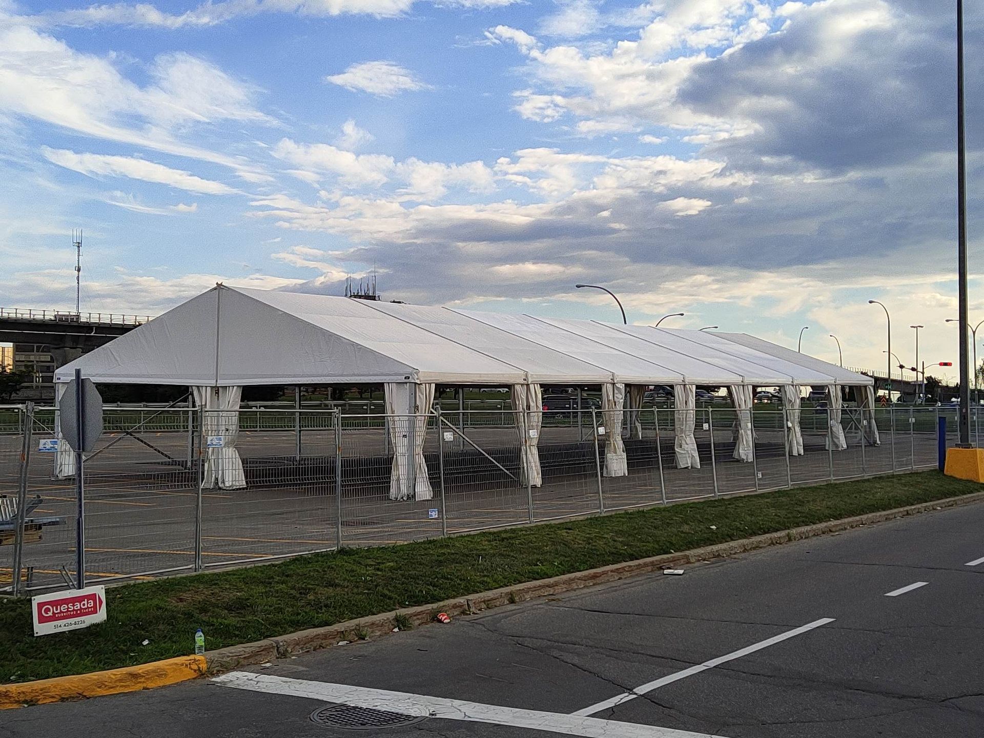 Une grande tente blanche est dressée au bord de la route.