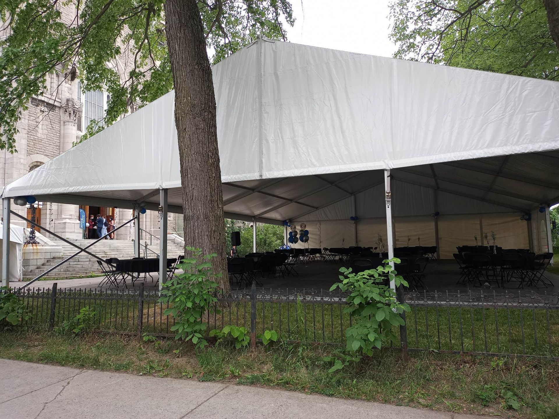 Une grande tente blanche est assise sous un arbre dans un parc