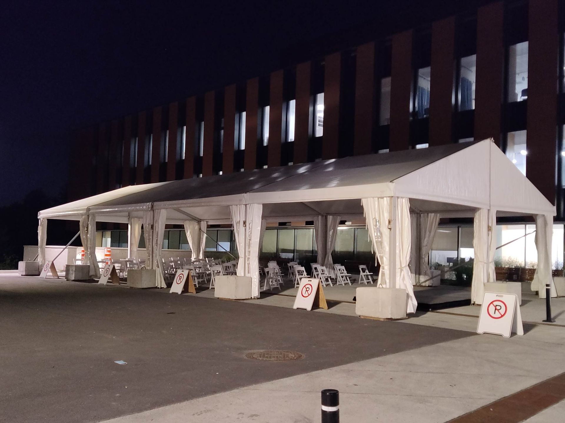 La nuit, une rangée de tentes est alignée devant un bâtiment.