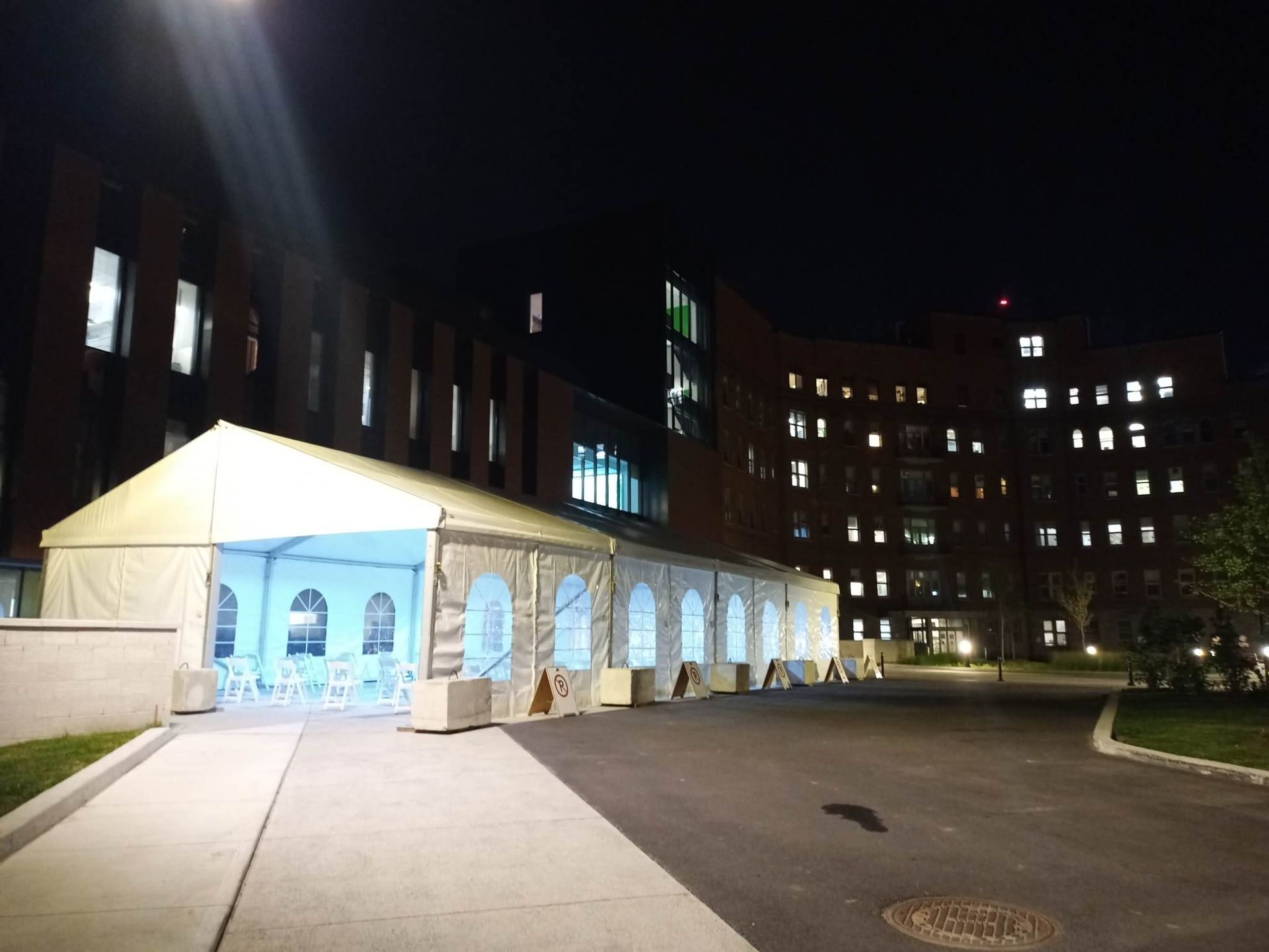 Un grand bâtiment avec une tente devant lui la nuit