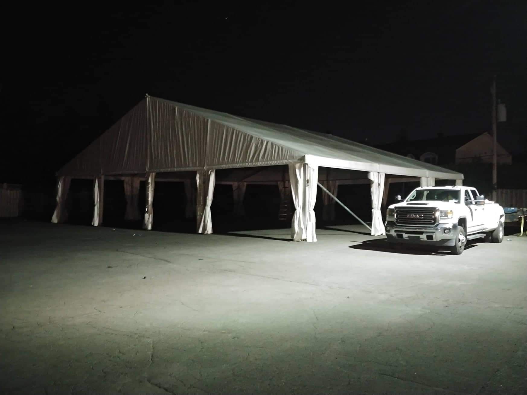 Un camion est garé devant une tente la nuit.