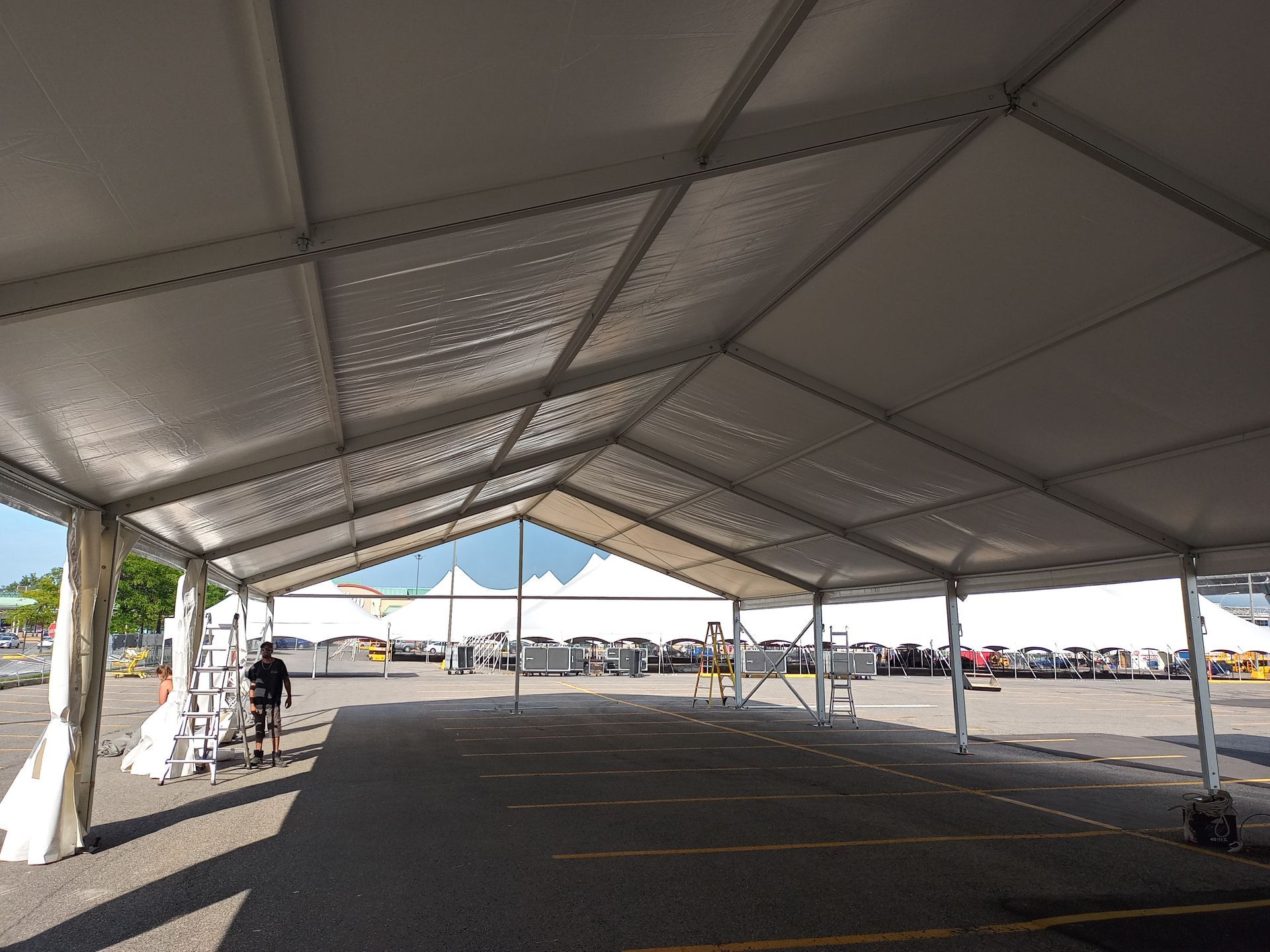 Une grande tente blanche est en construction sur un parking.