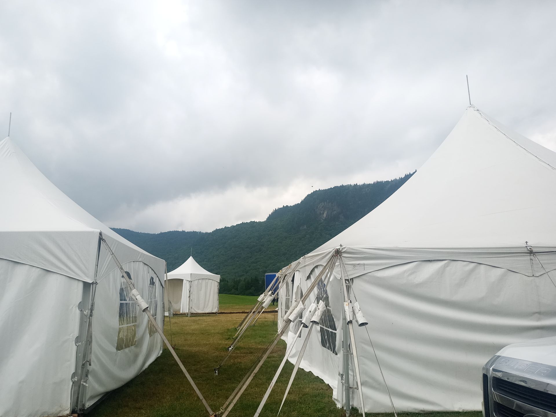 Une rangée de tentes blanches dans un champ avec des montagnes en arrière-plan