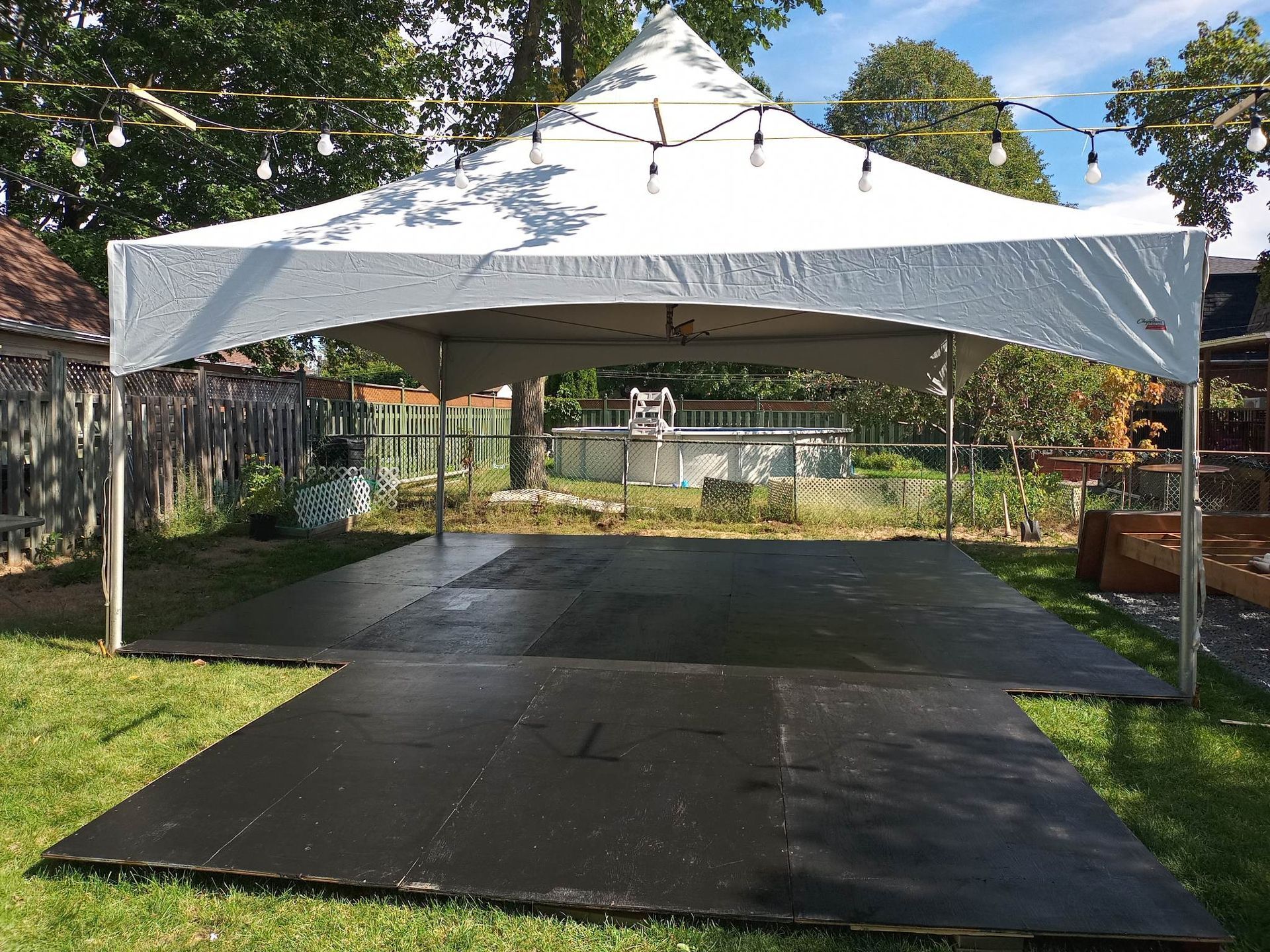 Une tente blanche est posée au sommet d’une piste de danse noire.