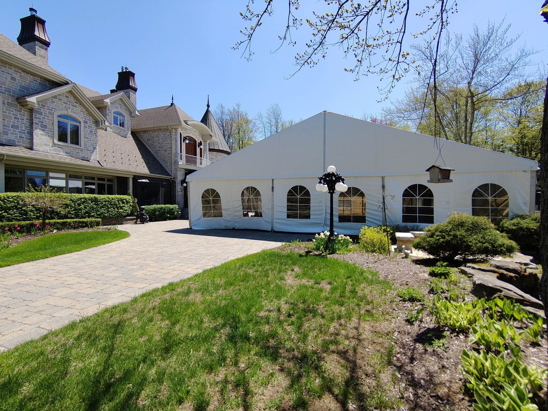Une grande tente blanche est installée devant une grande maison.