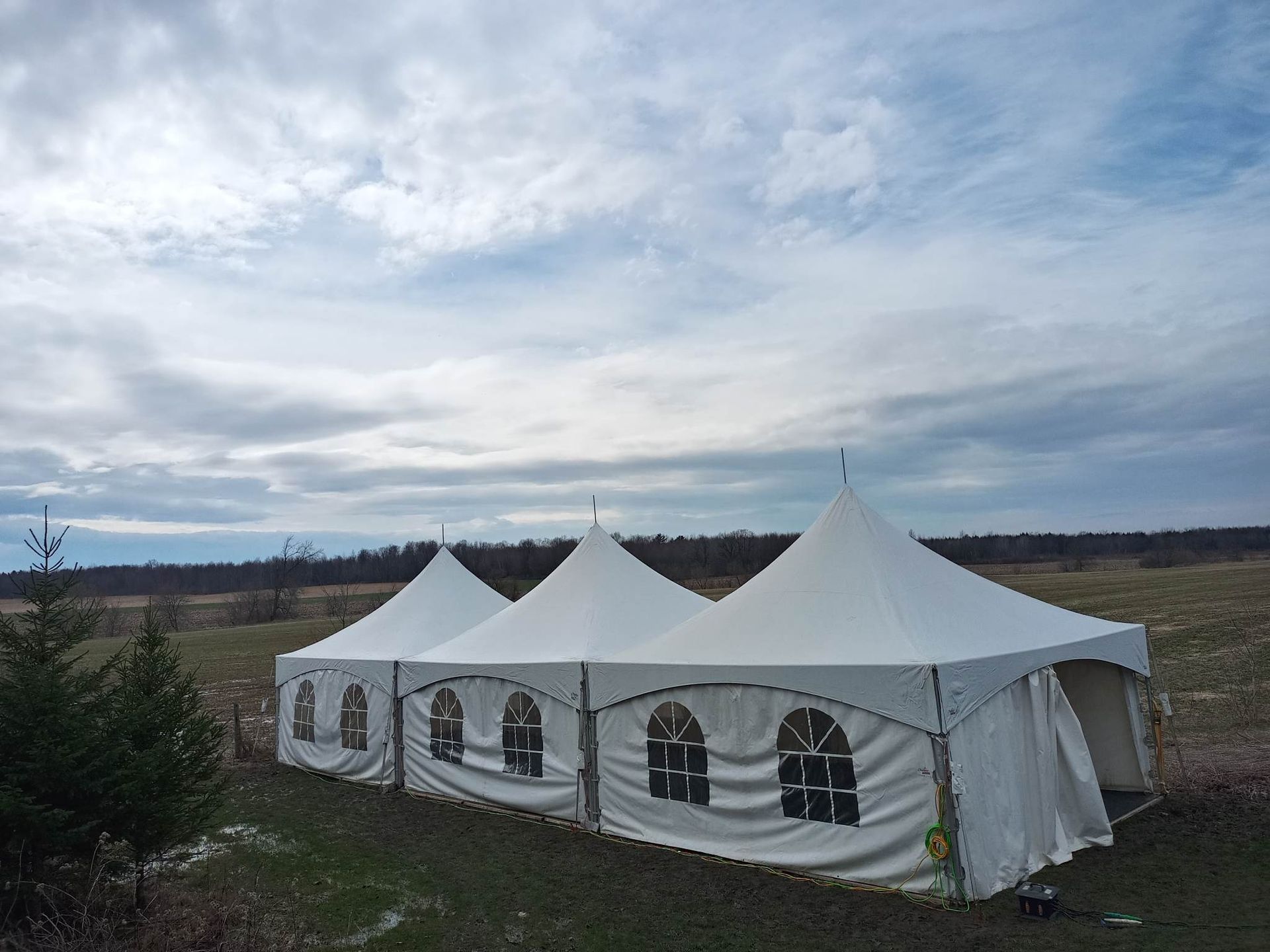 Une rangée de tentes blanches est alignée dans un champ.