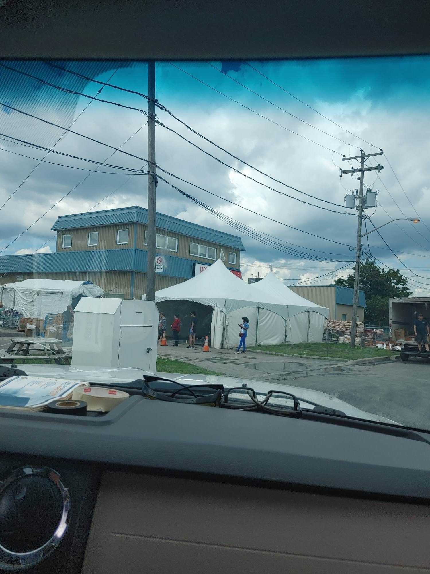Une voiture roule dans une rue avec des tentes et un bâtiment en arrière-plan.