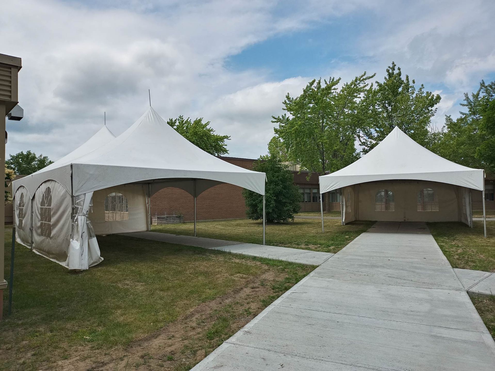 Deux tentes blanches sont assises l’une à côté de l’autre dans une zone herbeuse.