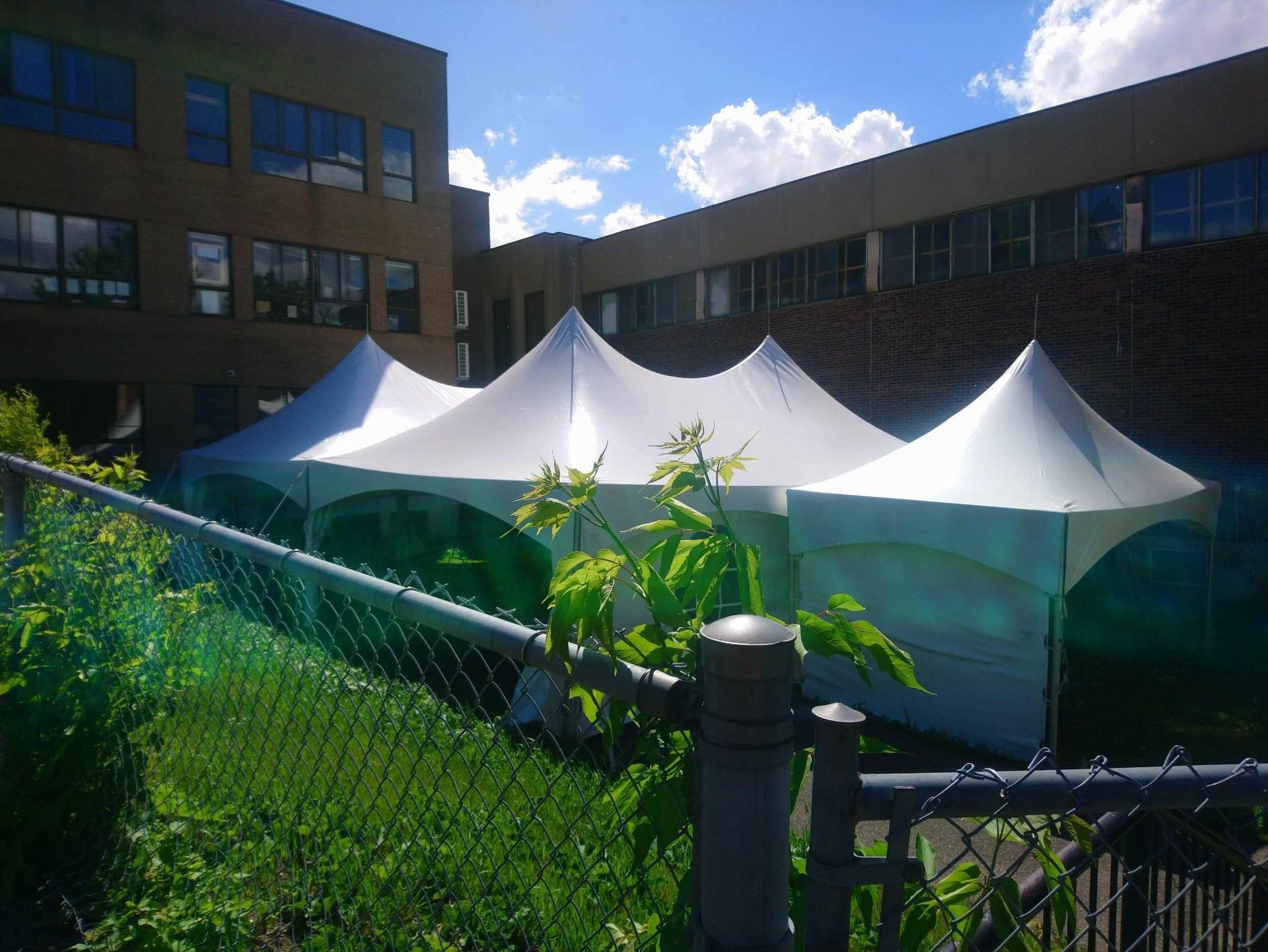 Une rangée de tentes blanches se trouve devant un grand bâtiment